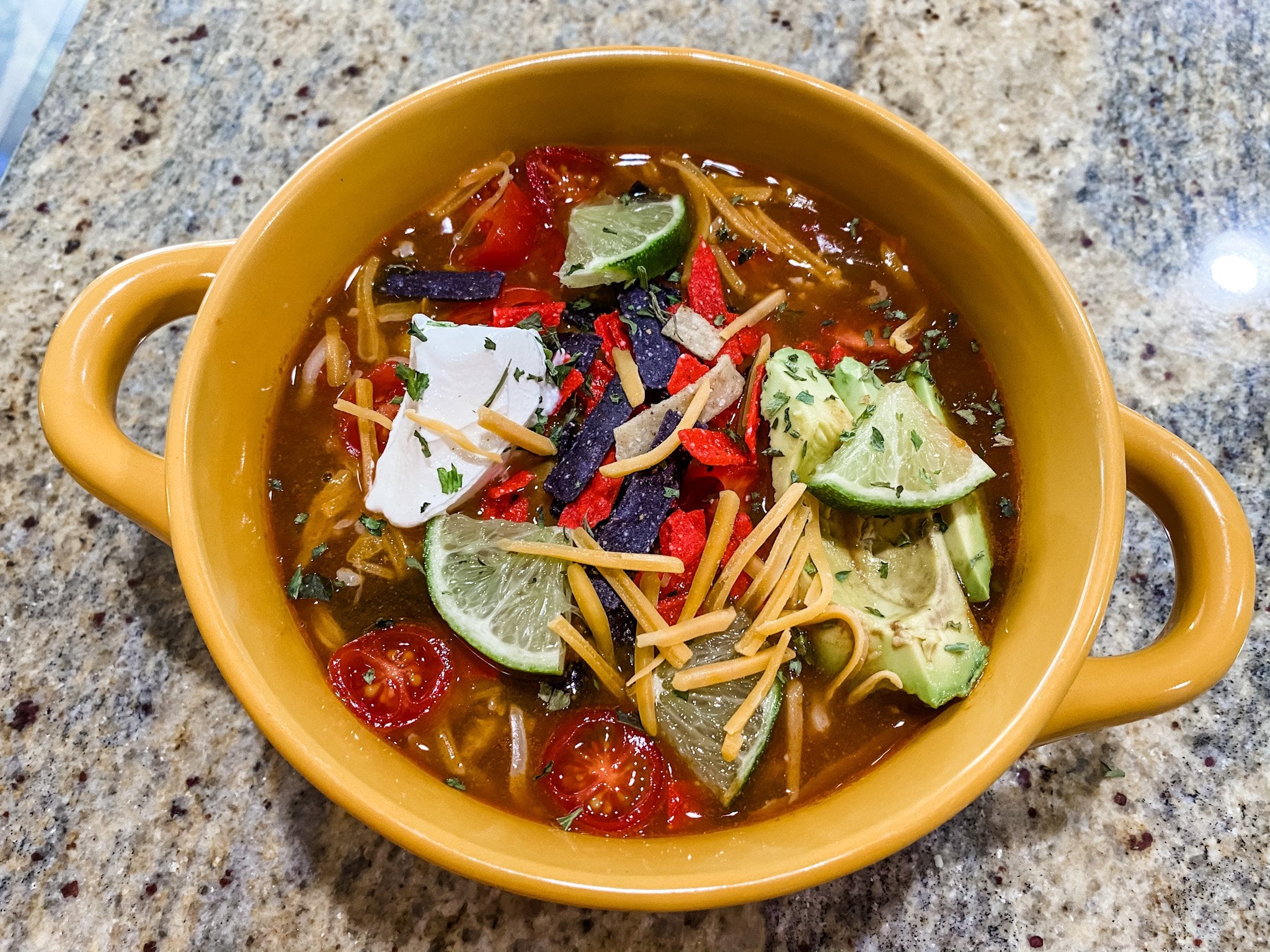 bowl of beef enchilada soup topped with sour cream and chips