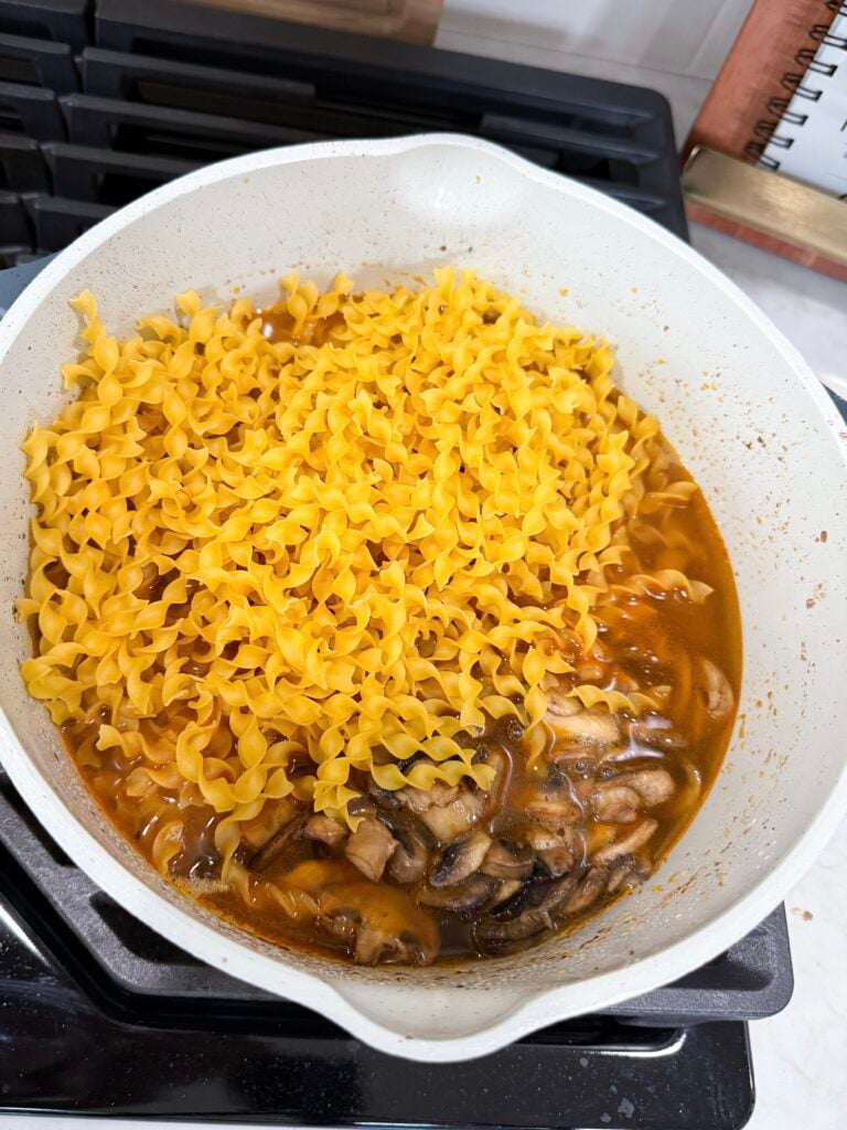 Add uncooked egg noodles to cooked turkey in stroganoff sauce in a large skillet on the oven