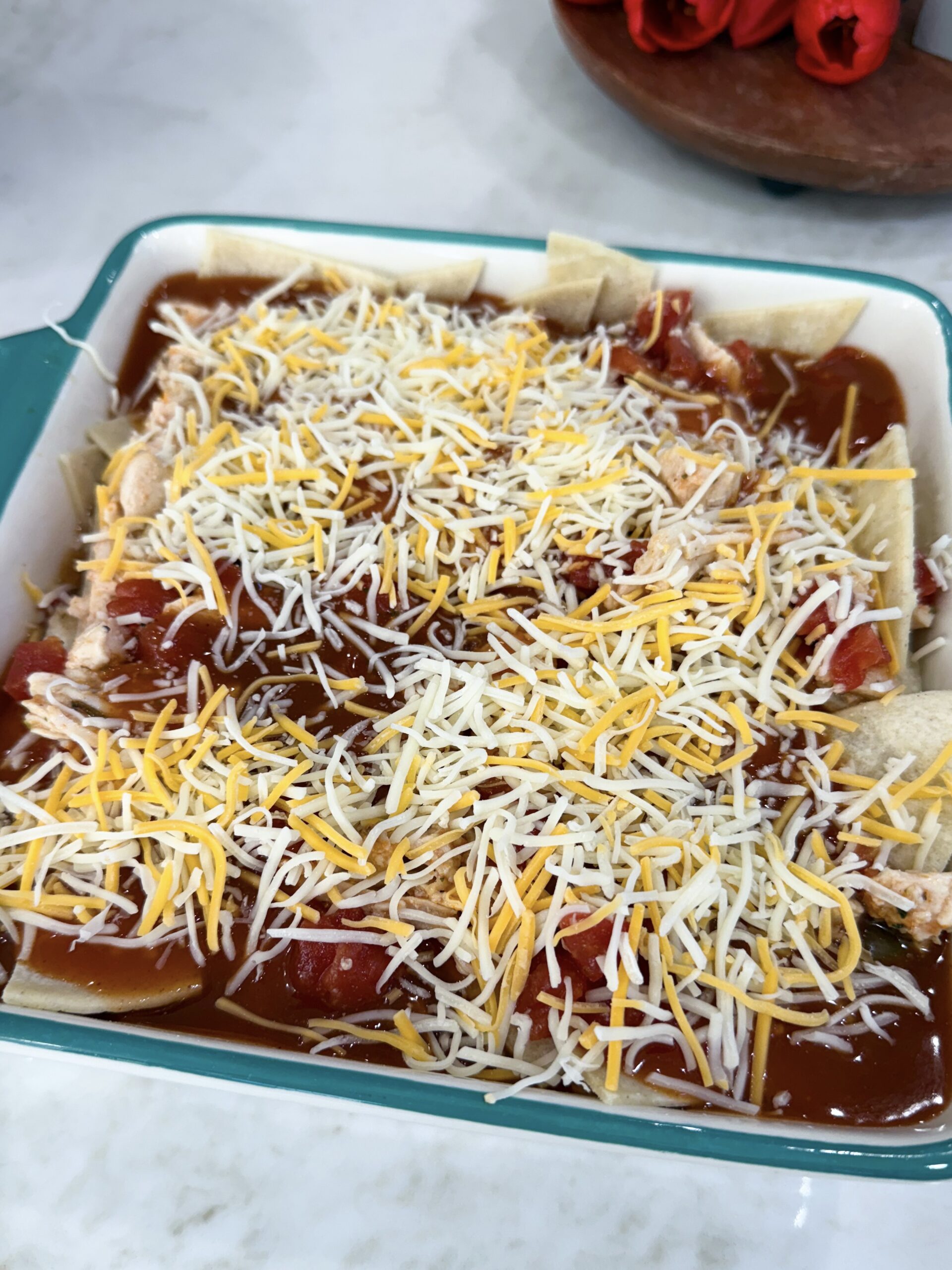 red chili enchiladas in the dish ready to be put into the oven