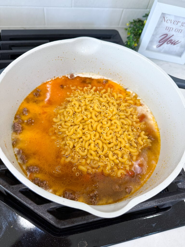 taco pasta recipe cooking in a pot with cheese just stirred in.