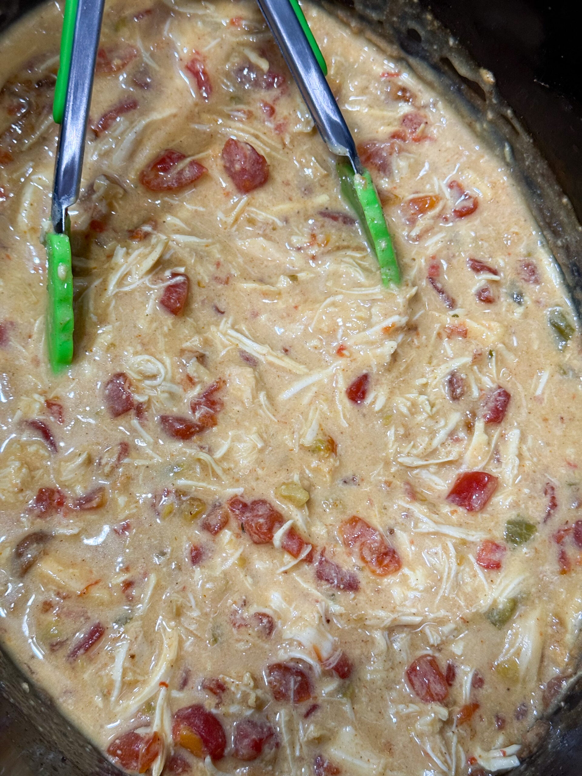 Shredding chicken in creamy queso sauce