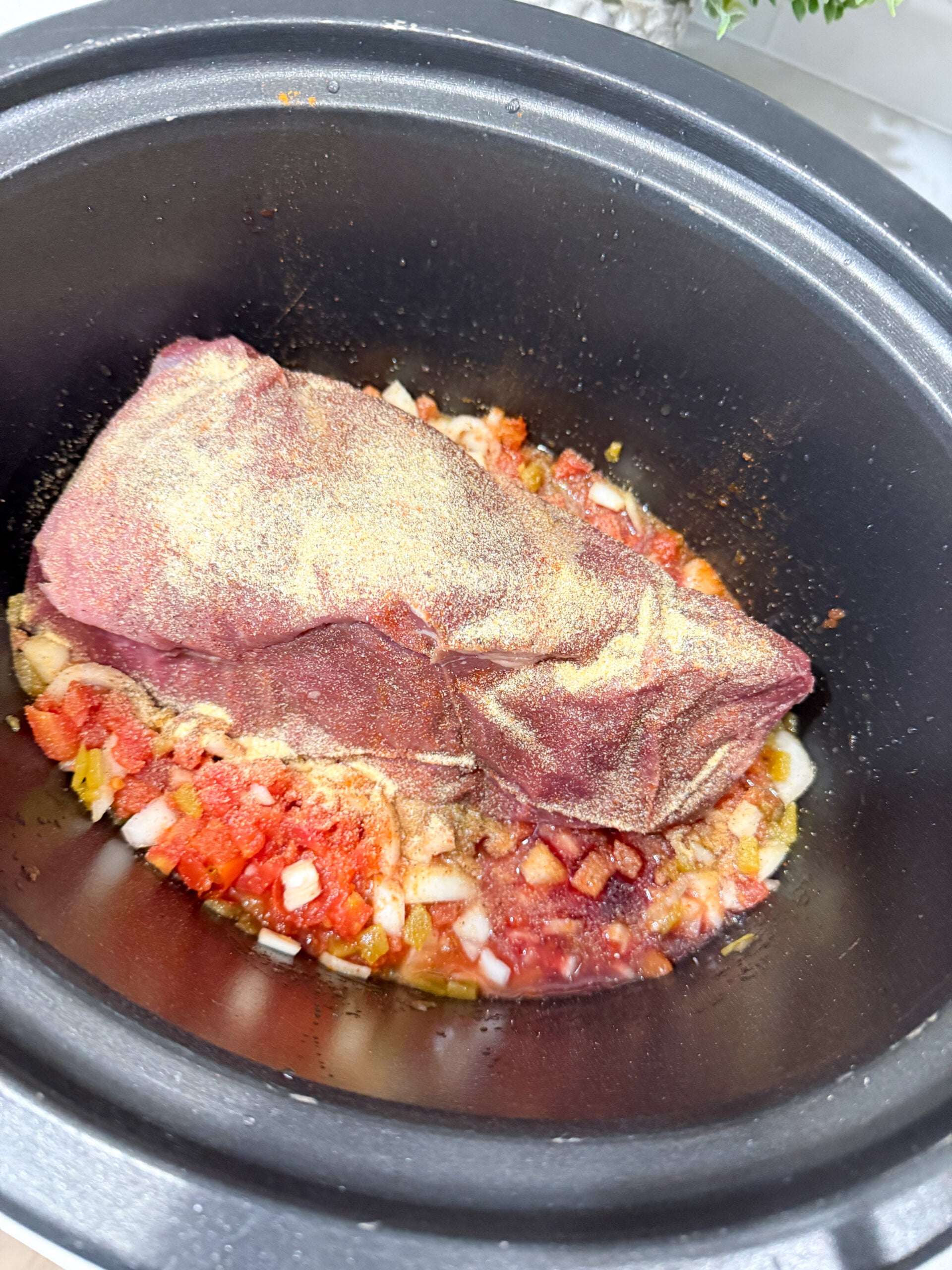 seasoned flank steak placed in slow cooker