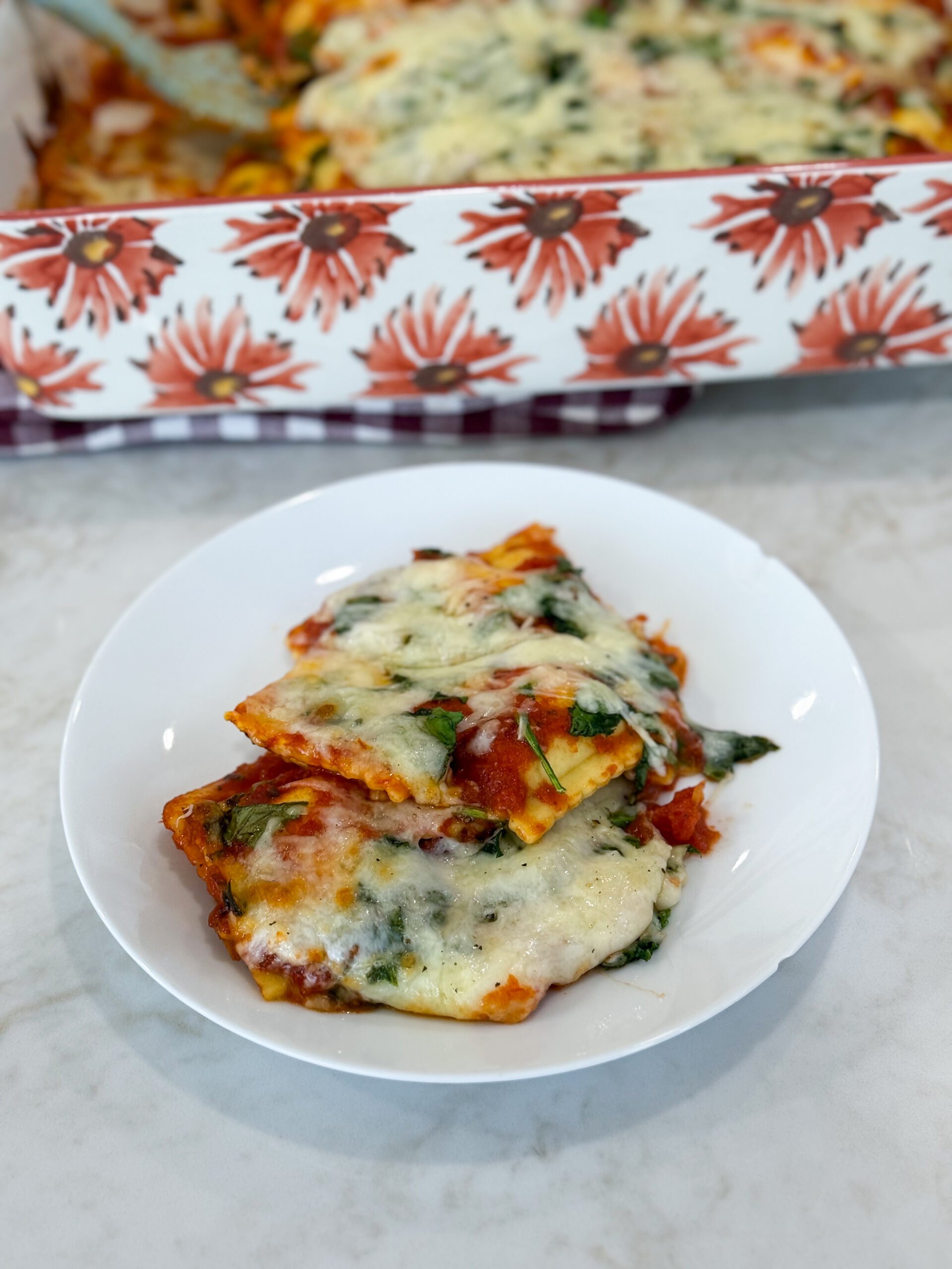 Simple cheese ravioli bake on a plate topped with melted mozzarella and herbs