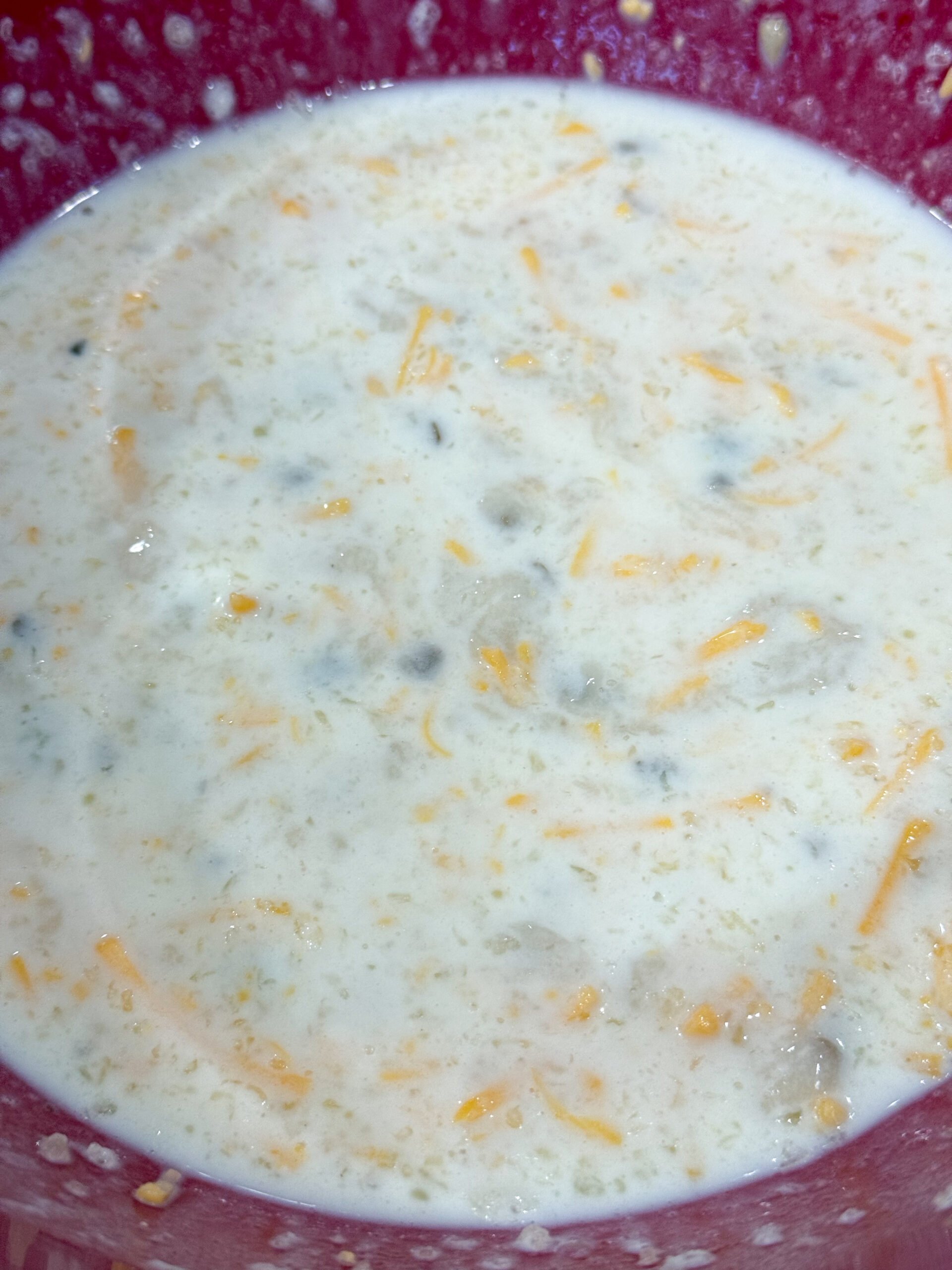 Mixing cream of mushroom soup, milk, and cheese in a bowl
