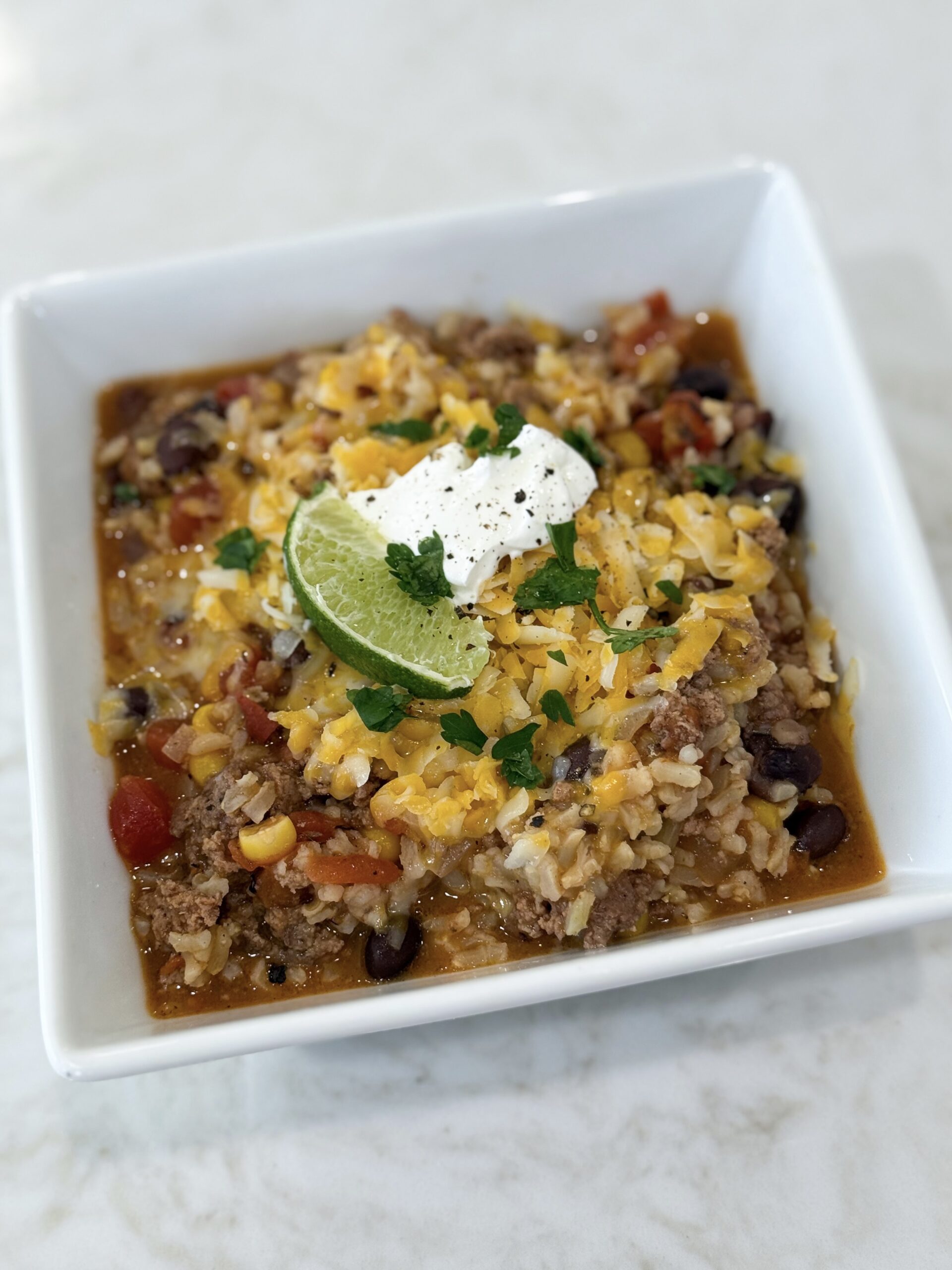 Mexican beef and rice one pot meal topped with melted cheese and fresh tomatoes