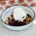 Baked berry cobbler topped with scoop of vanilla ice cream