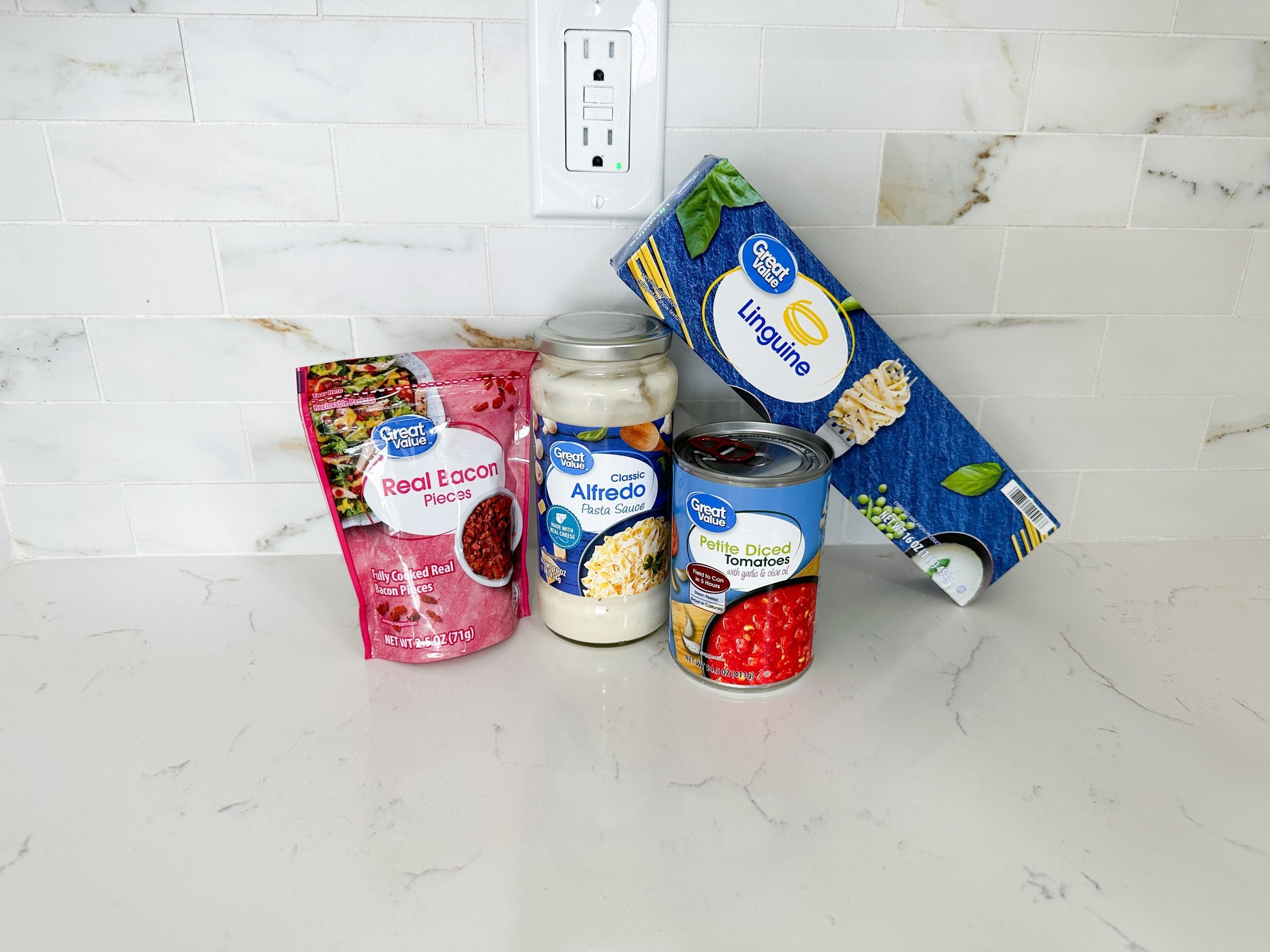 Ingredients for creamy tomato bacon pasta including pasta, Alfredo sauce, and bacon bits