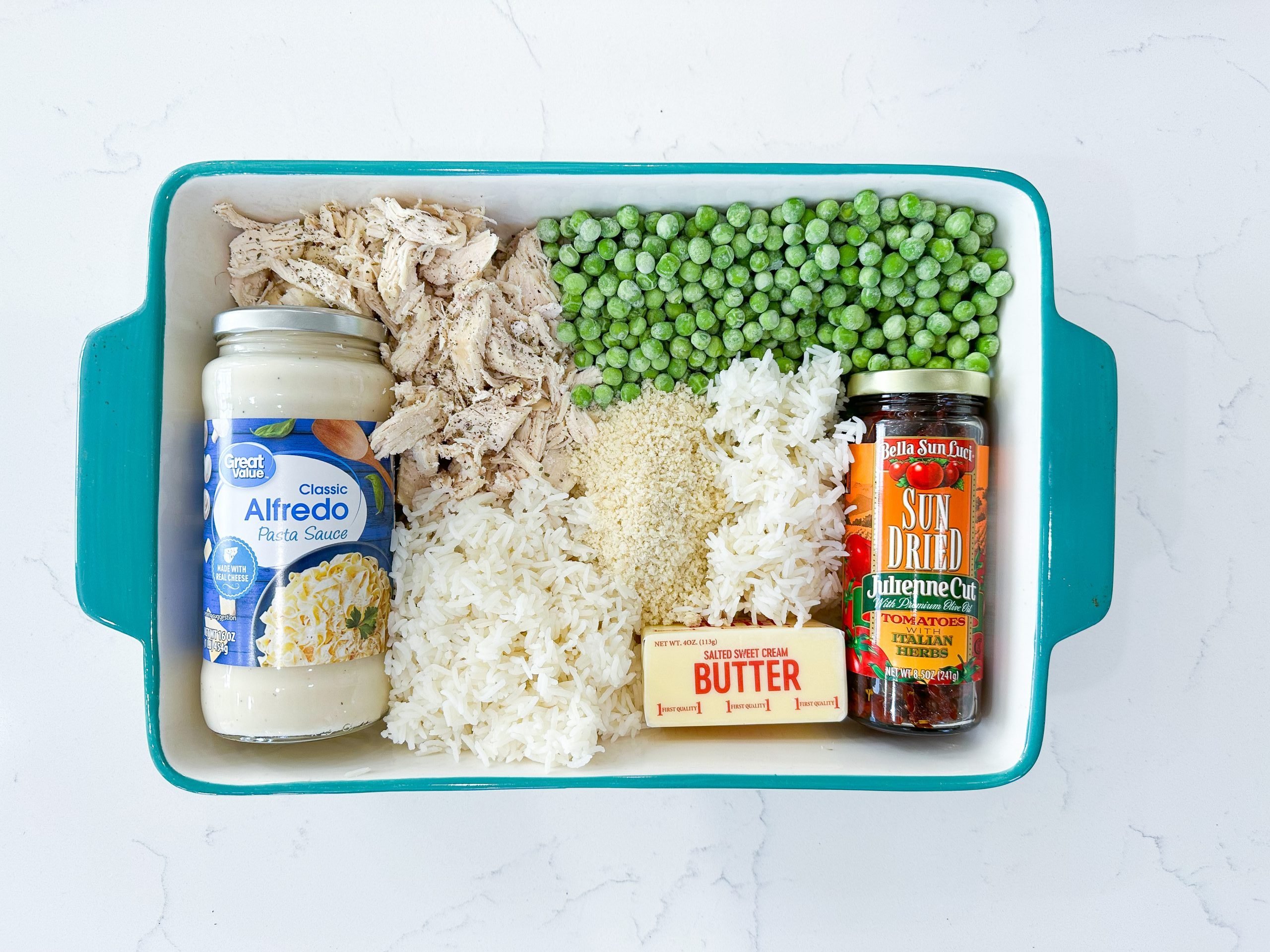 rice, chicken, Alfredo sauce, peas, and breadcrumbs on a counter