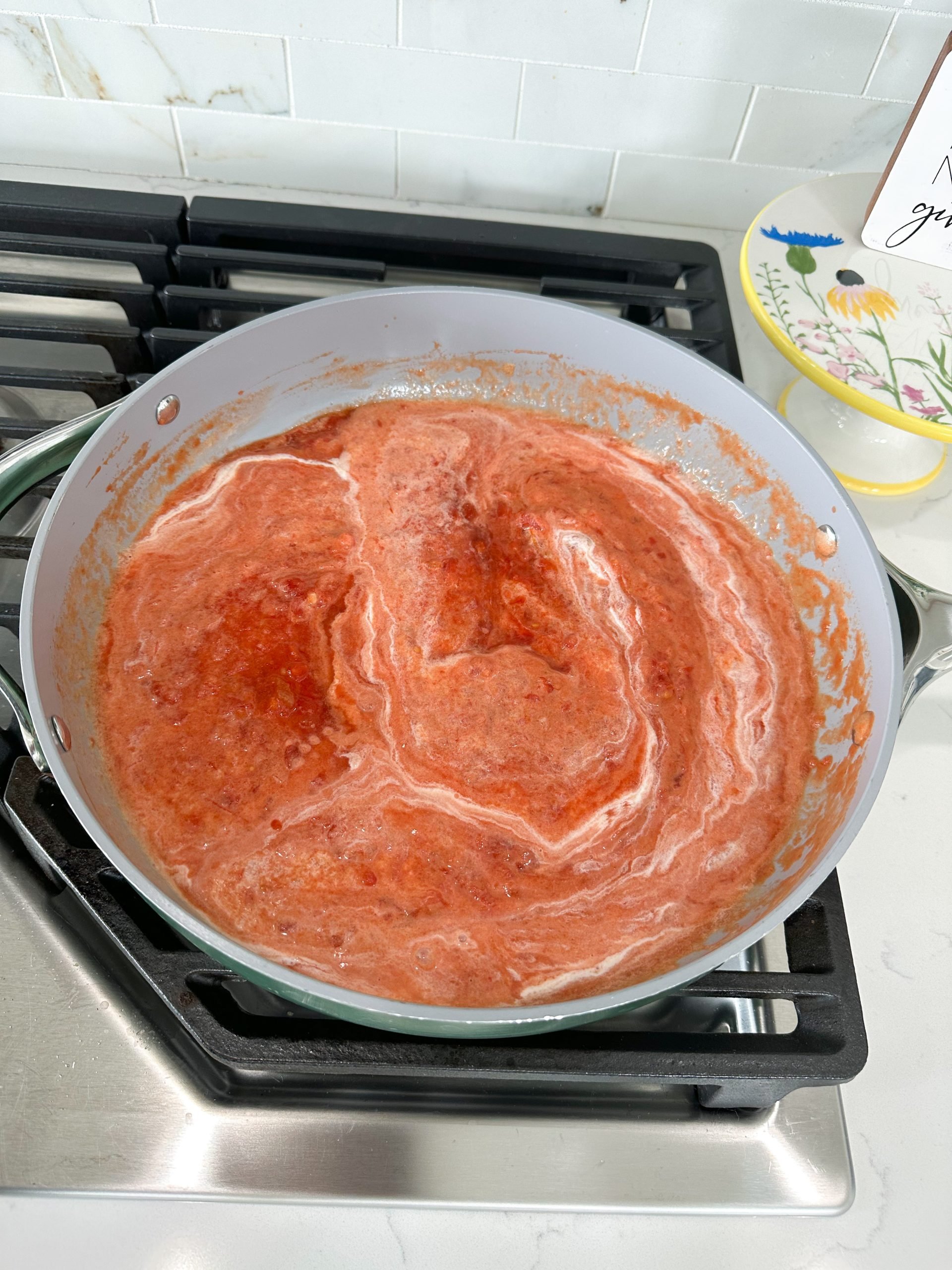 crushed tomatoes and cream simmering in skillet