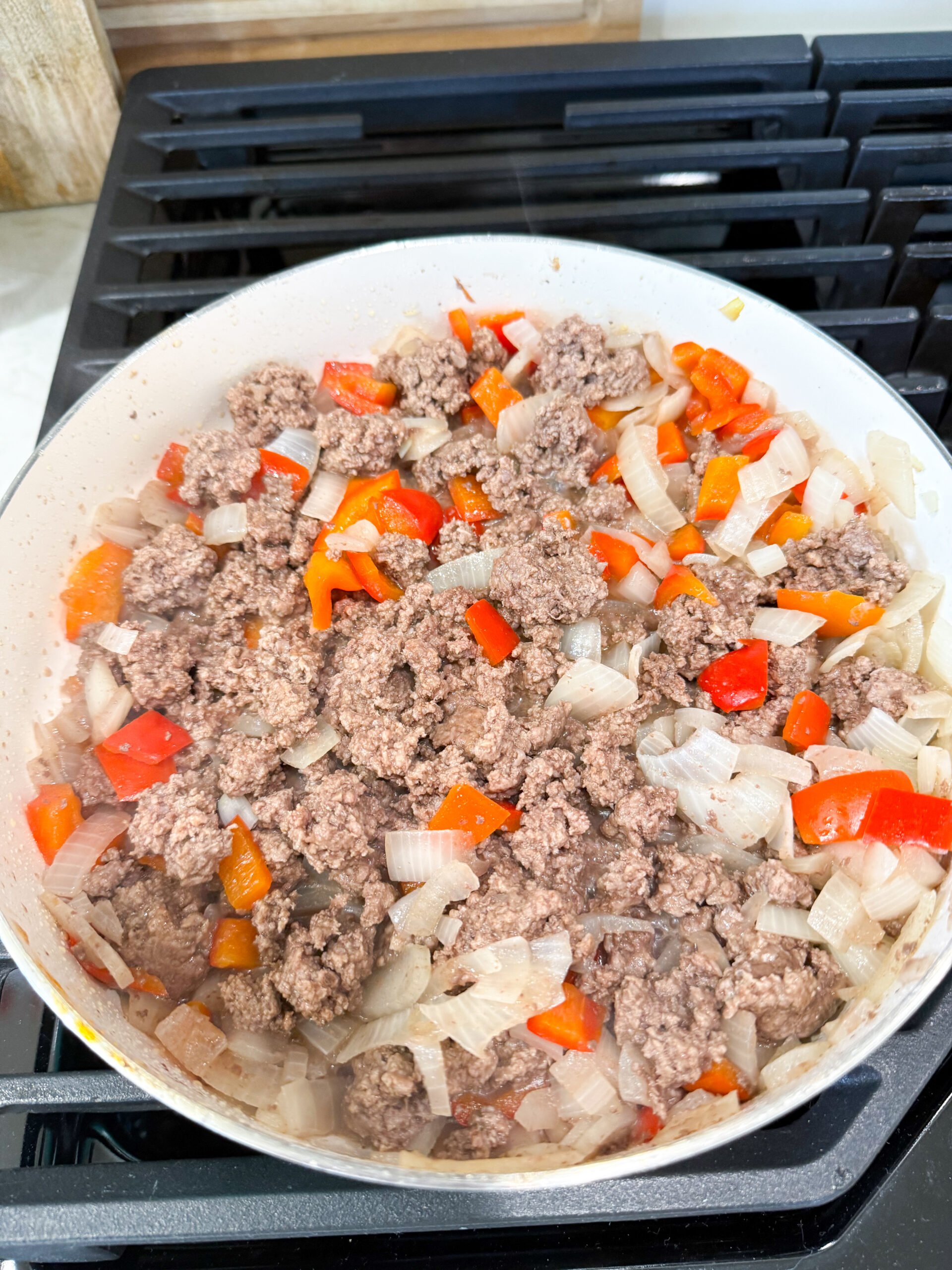 Ground beef, onion, and peppers cooking in skillet