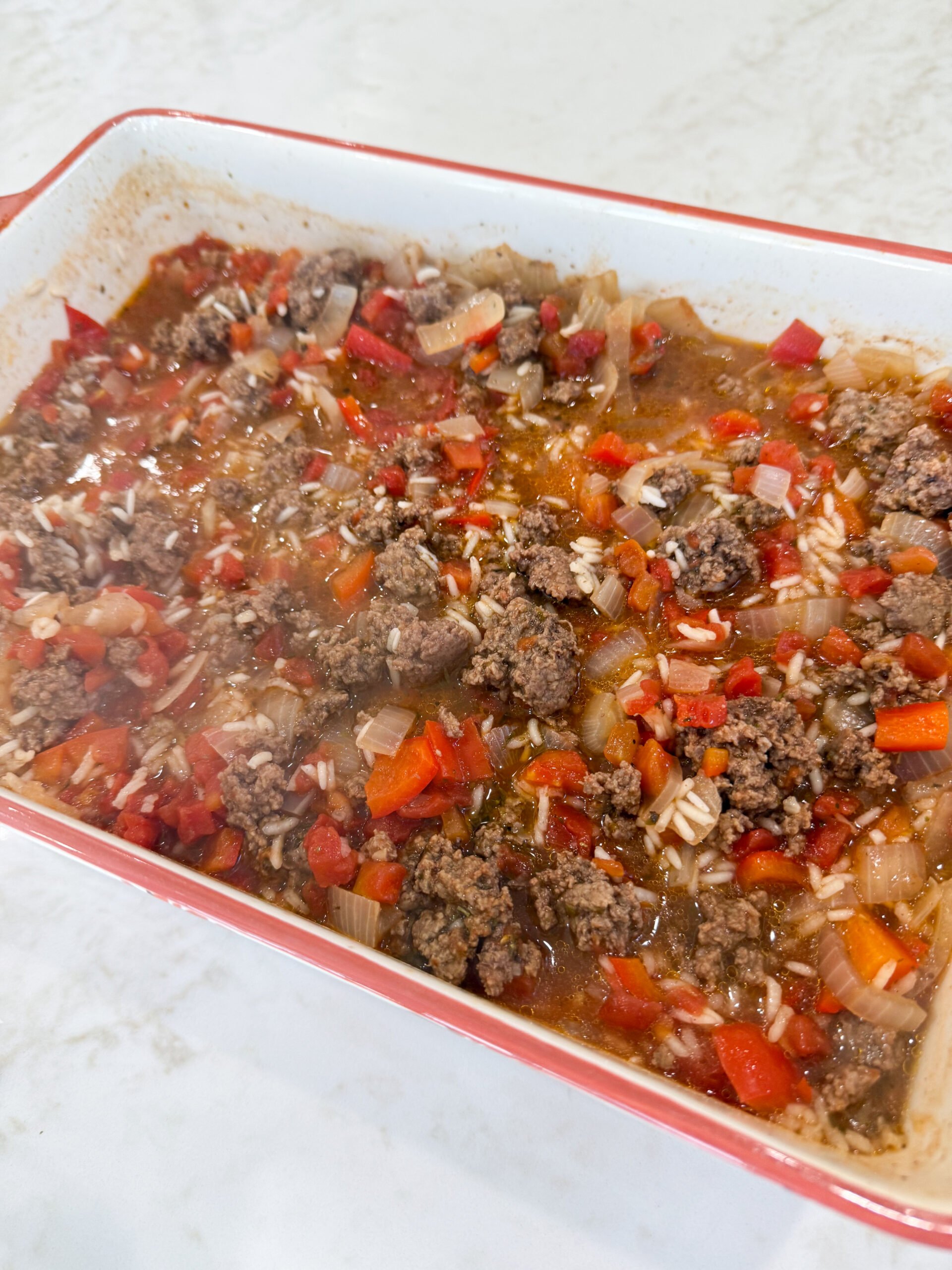 Stirring rice, beef, and cheese in casserole dish before baking