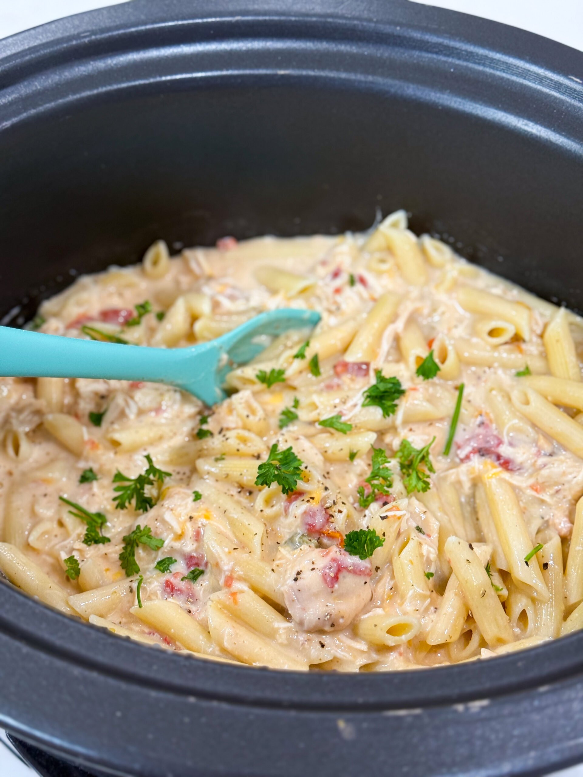 Creamy chicken pasta in slow cooker topped with cheese