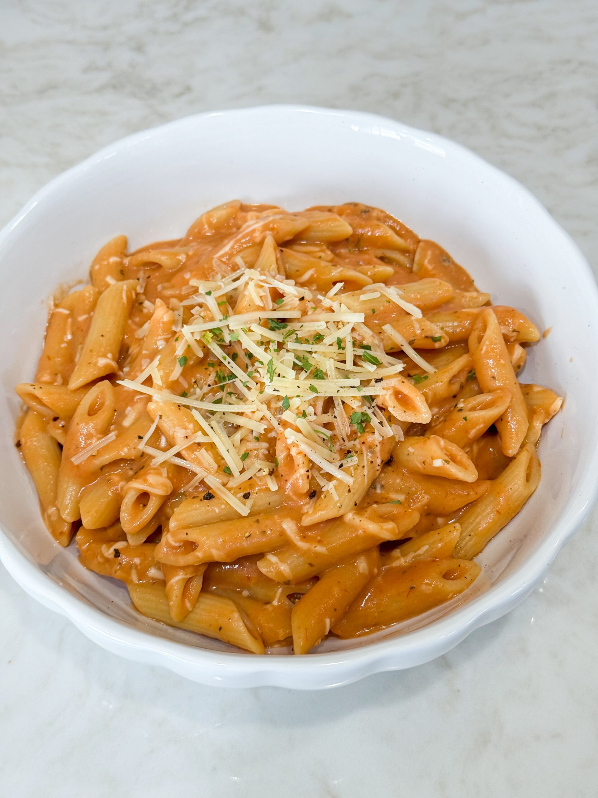 Creamy penne pasta in a pot with melted cheese on top