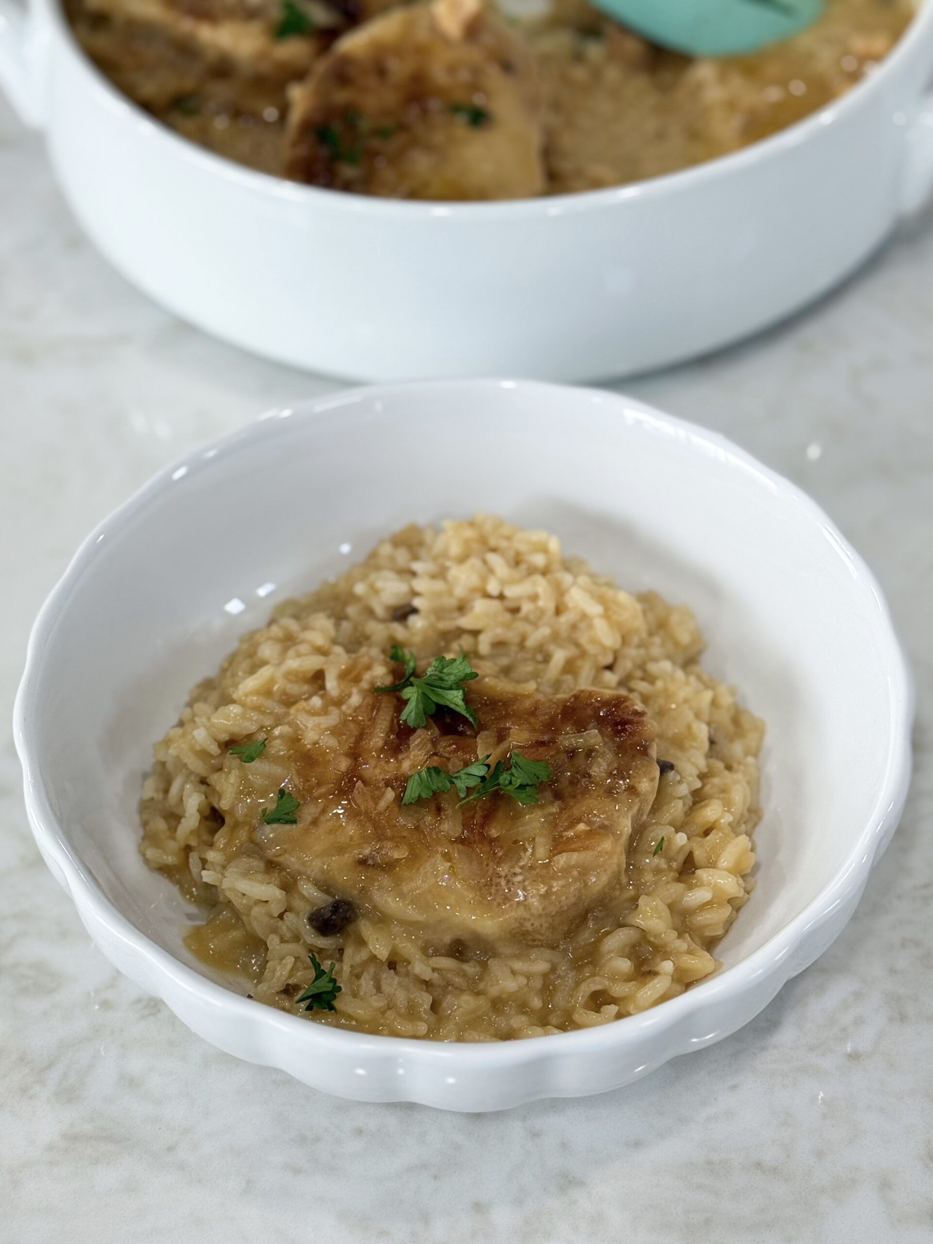 Serving of No Peek Pork Chop Casserole on a plate with rice and pork chop.