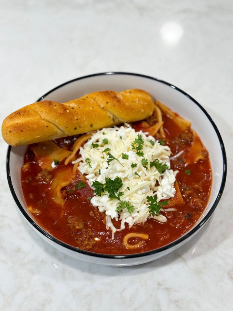 Bowl of lasagna soup topped with melted cheese
