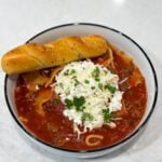 Slow cooker lasagna soup in bowl with spoon and herbs