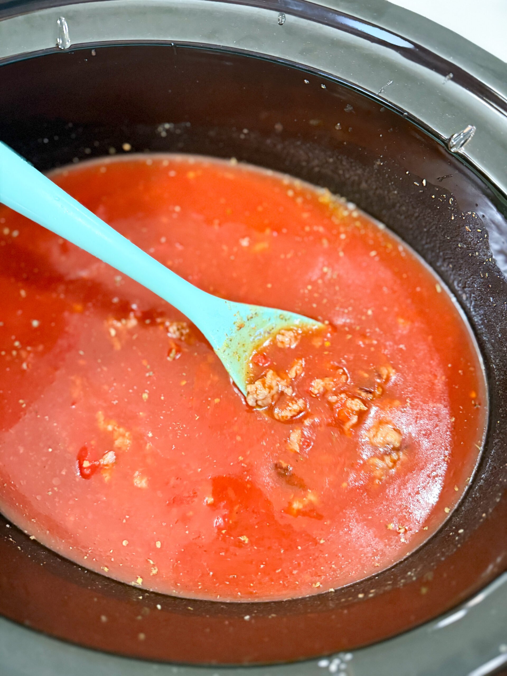 Adding ingredients to slow cooker for lasagna soup