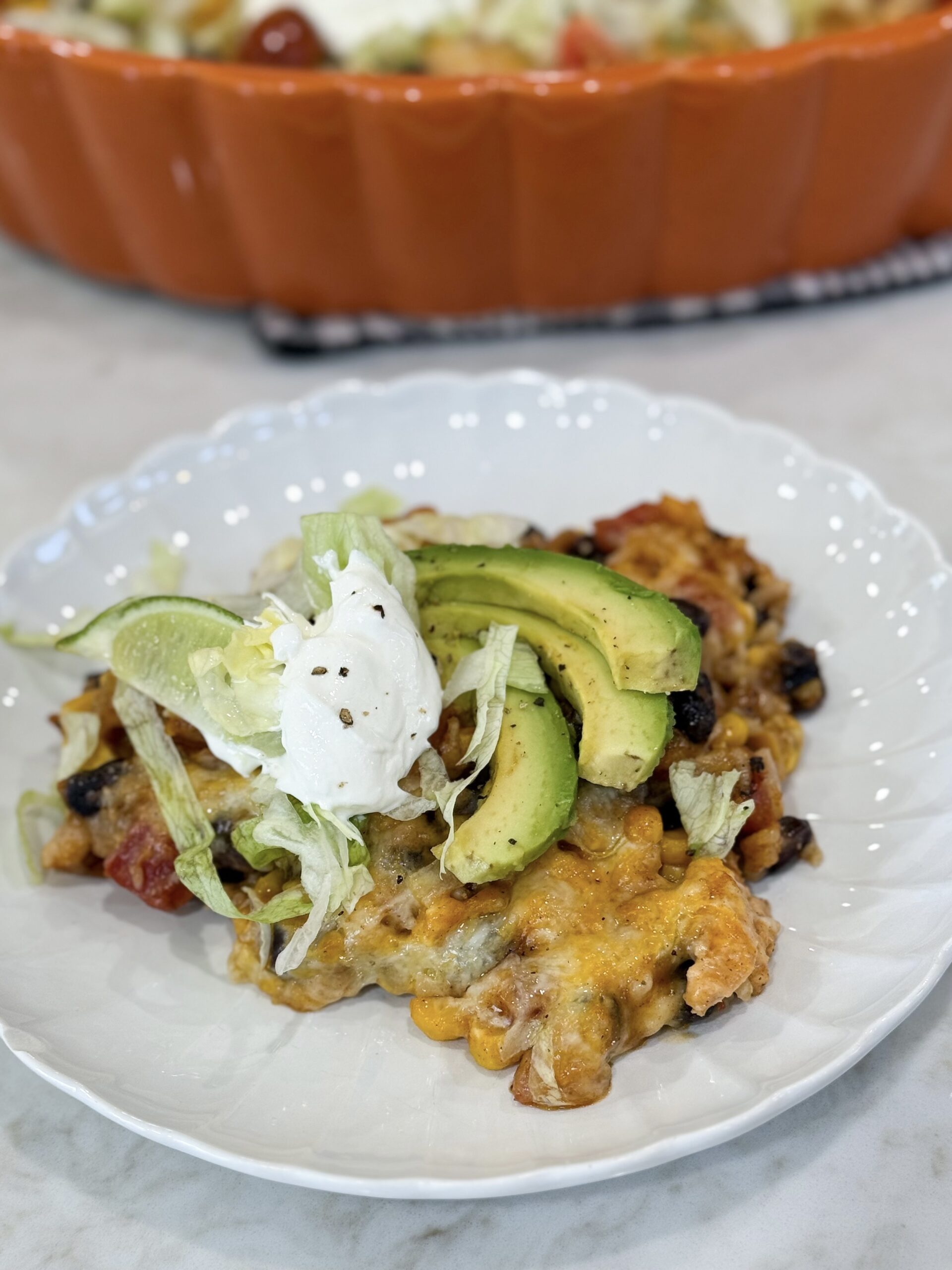 Fiesta chicken casserole on plate topped with melted cheese and fresh toppings