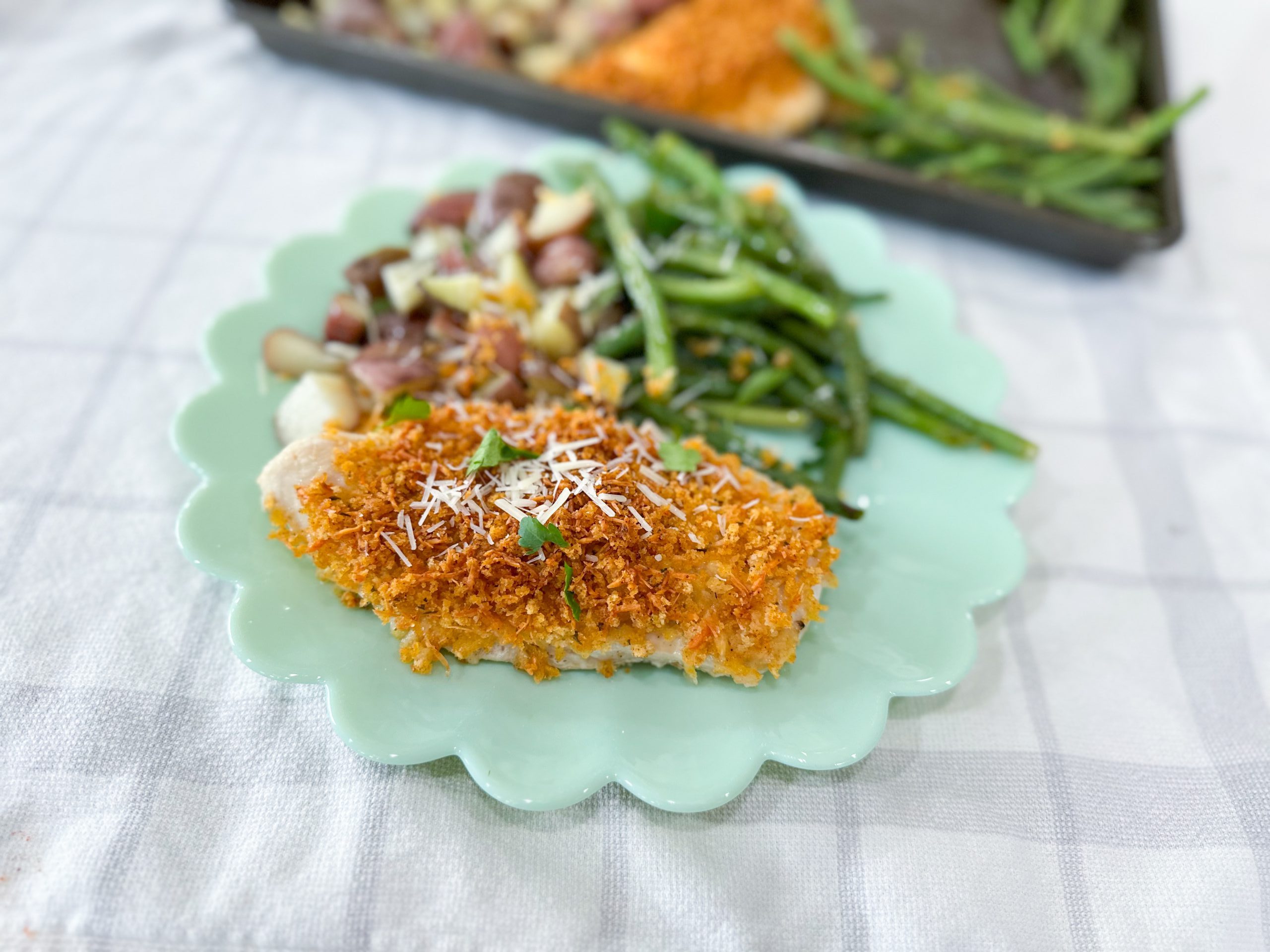 Golden brown Parmesan Crusted Chicken with perfectly roasted green beans and tender red potatoes on a sheet pan, ready to serve.