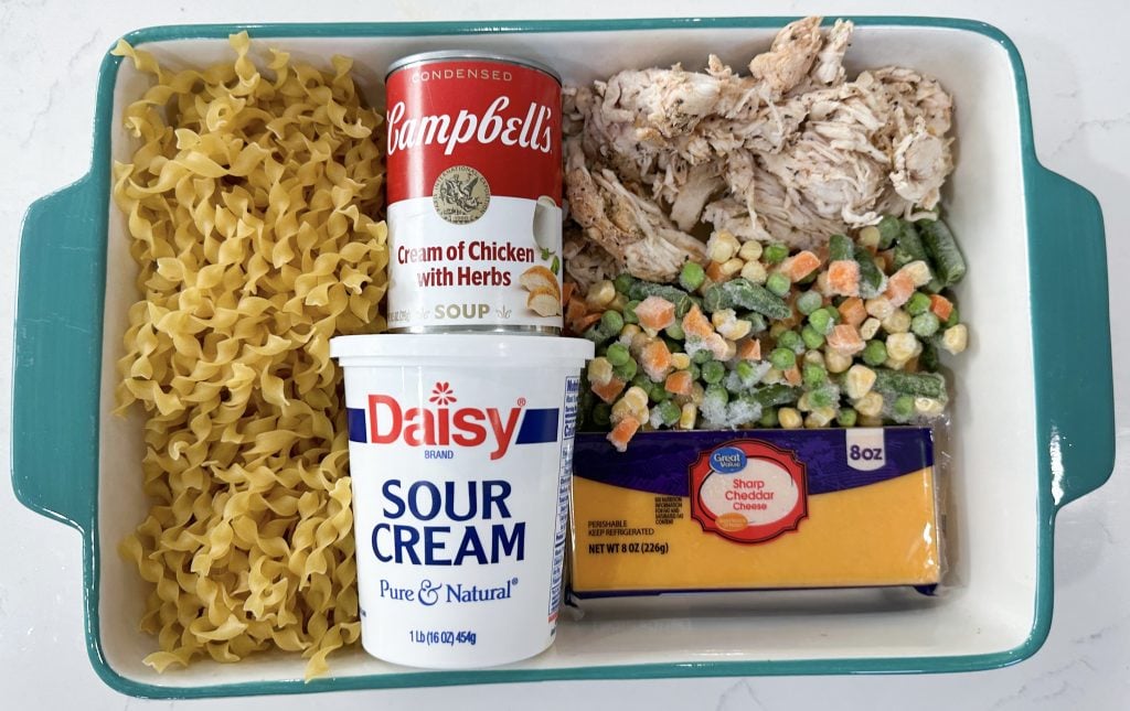 Chicken noodle casserole in a baking dish topped with melted cheese