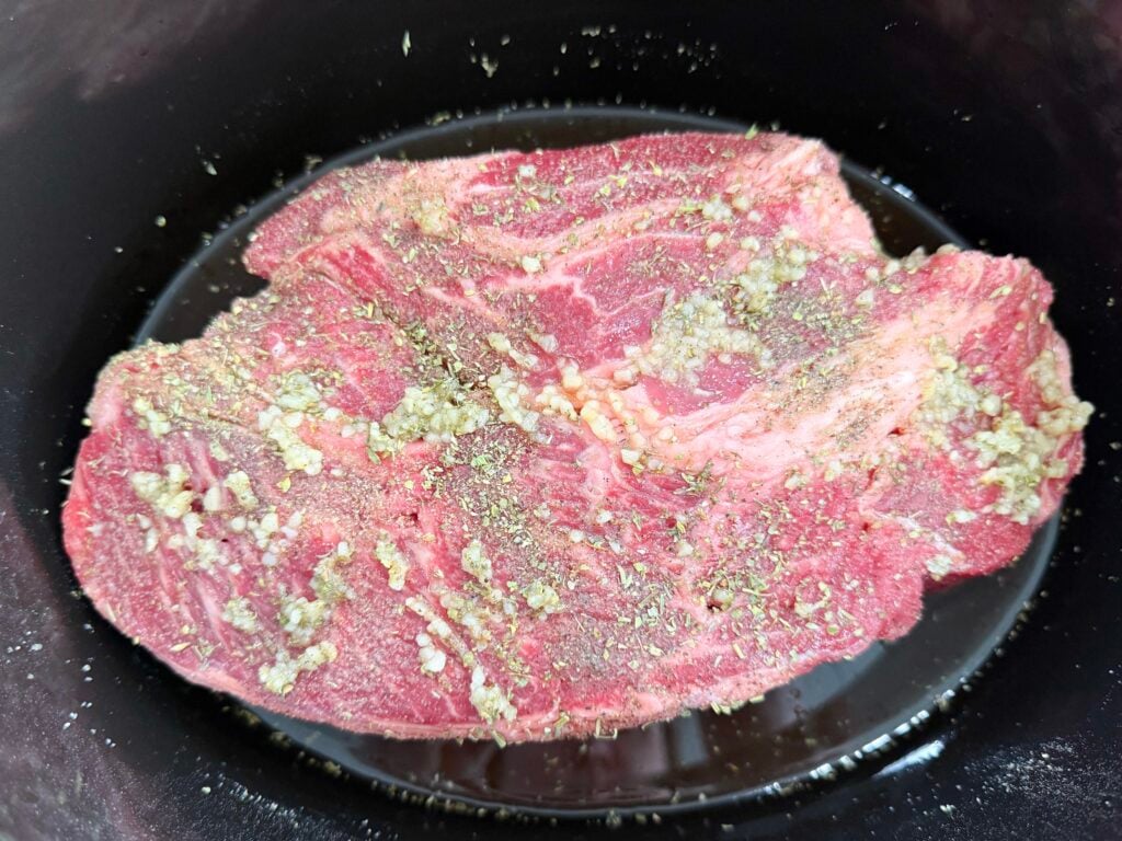 beef seasoned in a black slow cooker