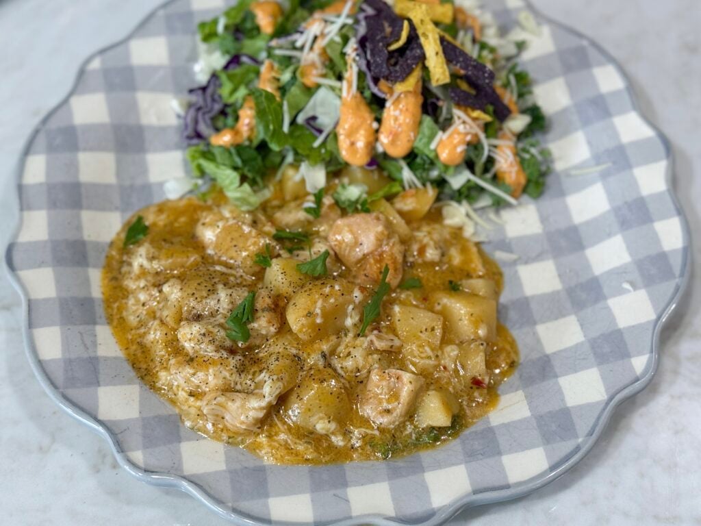 chicken and potatoes on a blue and white plate with salad
