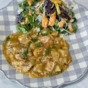 chicken and potatoes on a blue and white plate with salad