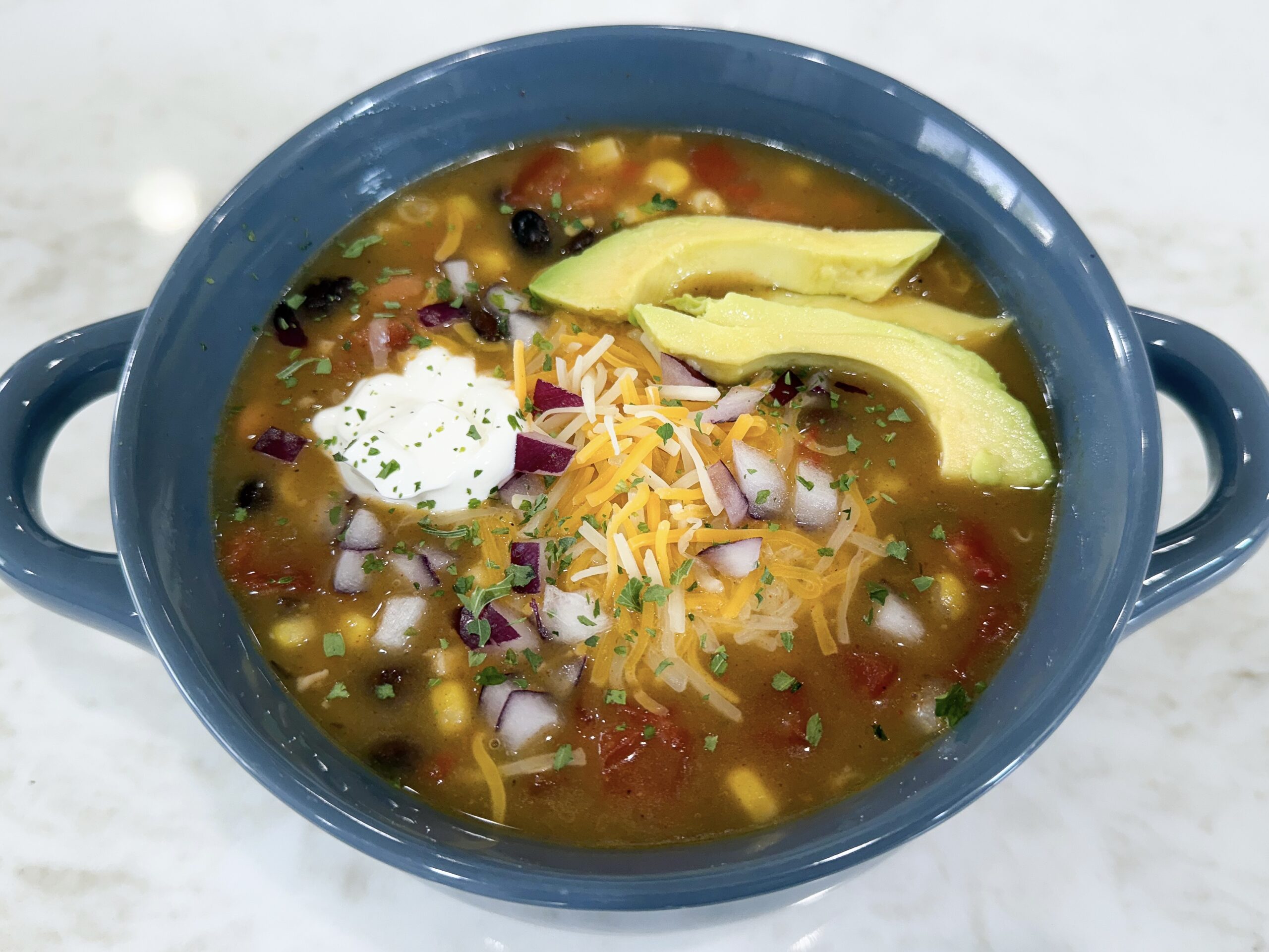 Bowl of 8 Can Chicken Taco Soup topped with sour cream and cheese