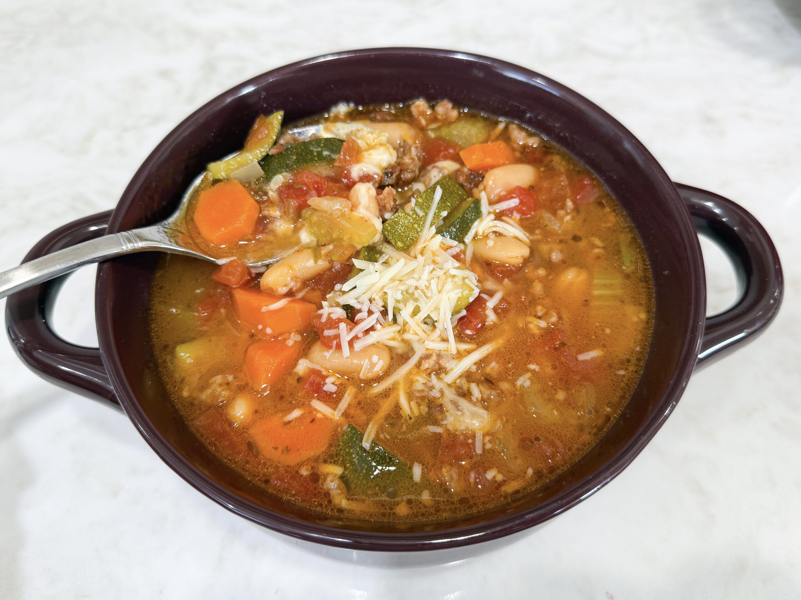 Bowl of Italian Vegetable and Sausage Soup topped with Parmesan