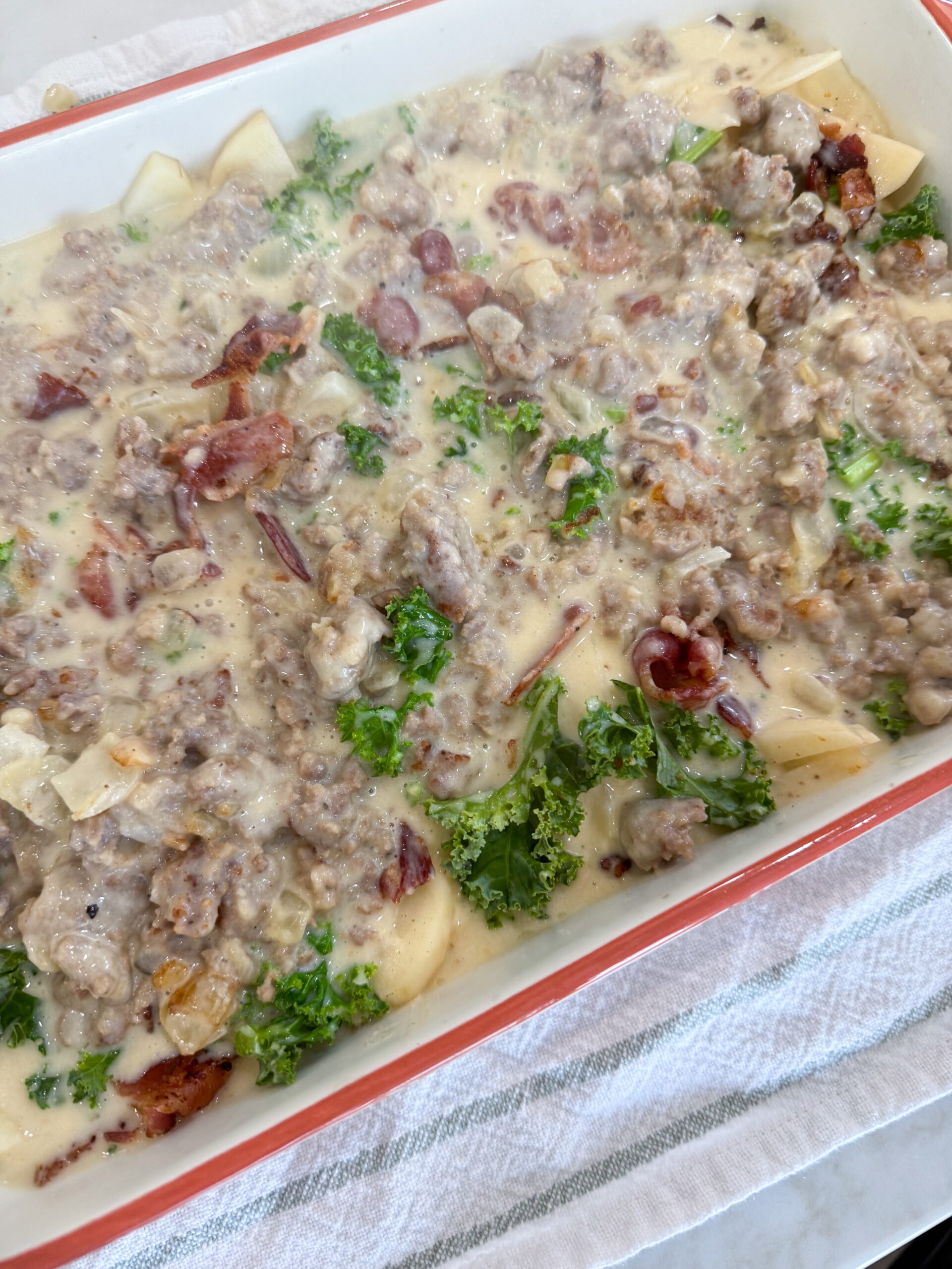 Casserole layered with sausage cream sauce and sprinkled with Parmesan cheese before baking.