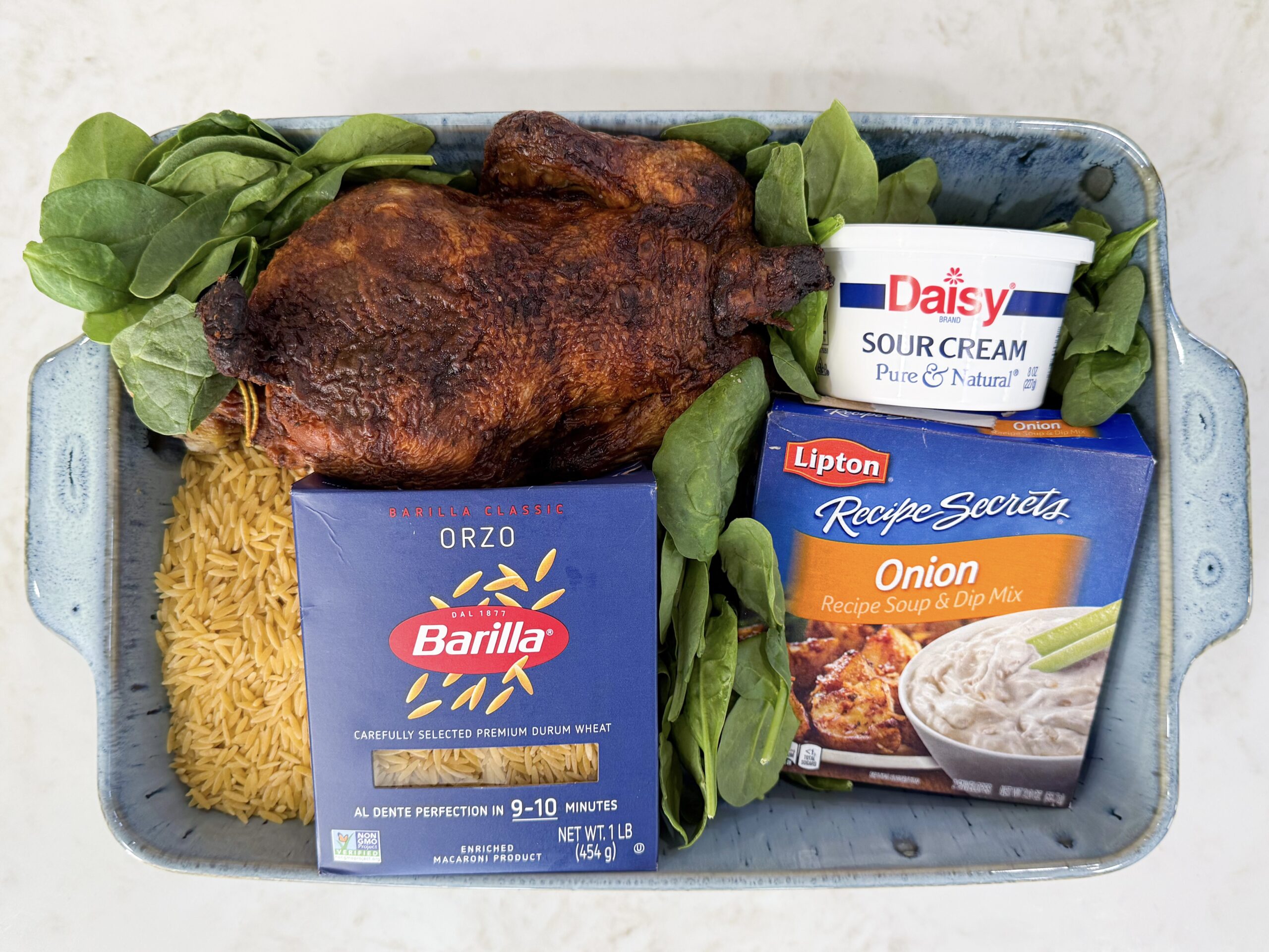 Ingredients for Spinach Chicken Orzo Casserole including orzo pasta, chicken broth, onion soup mix, shredded chicken, spinach, sour cream, mushroom soup, and mozzarella.