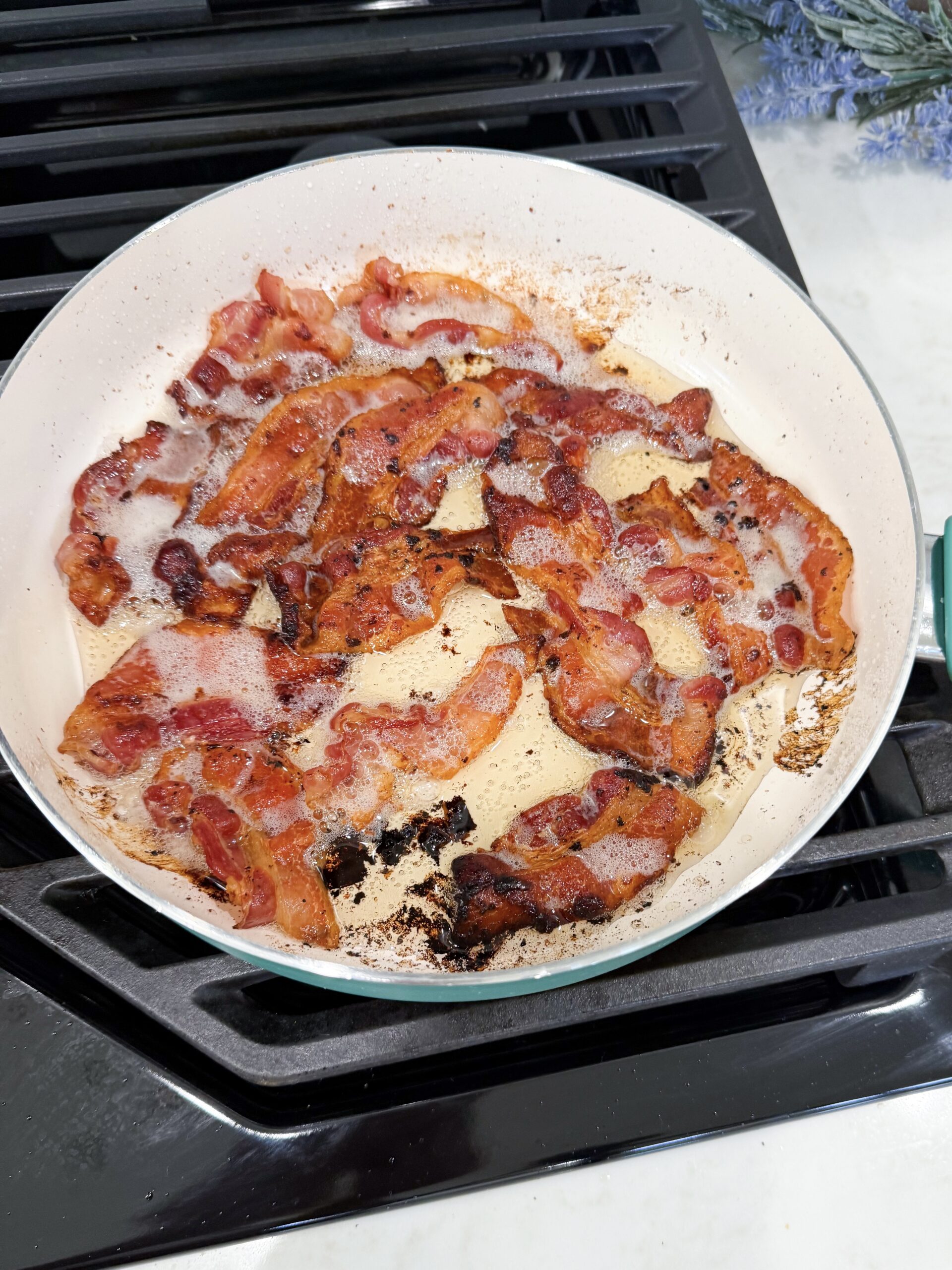 Crizpy bacon peices in hot grease in a pan.