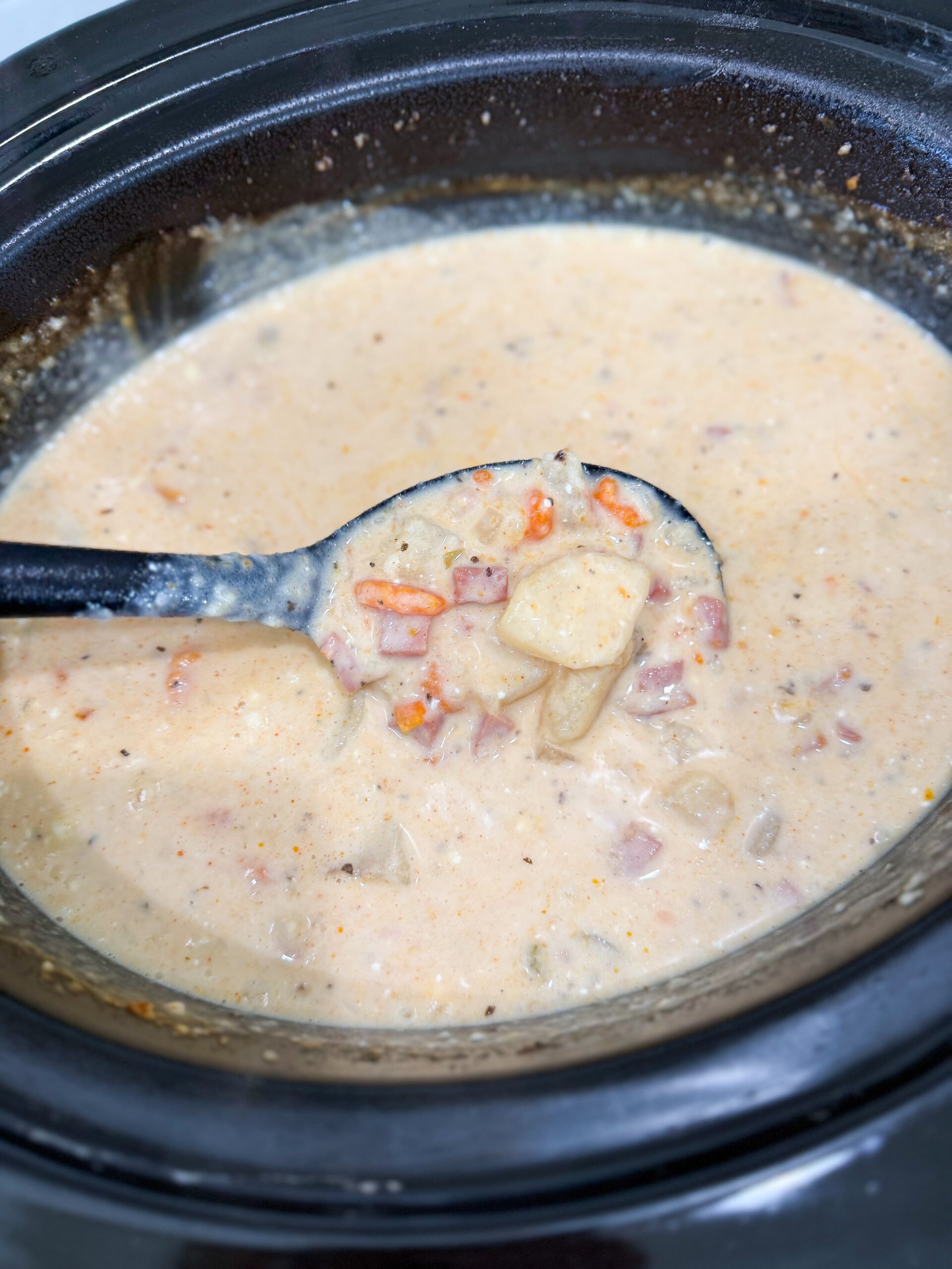 Sour cream and shredded cheese being stirred into soup