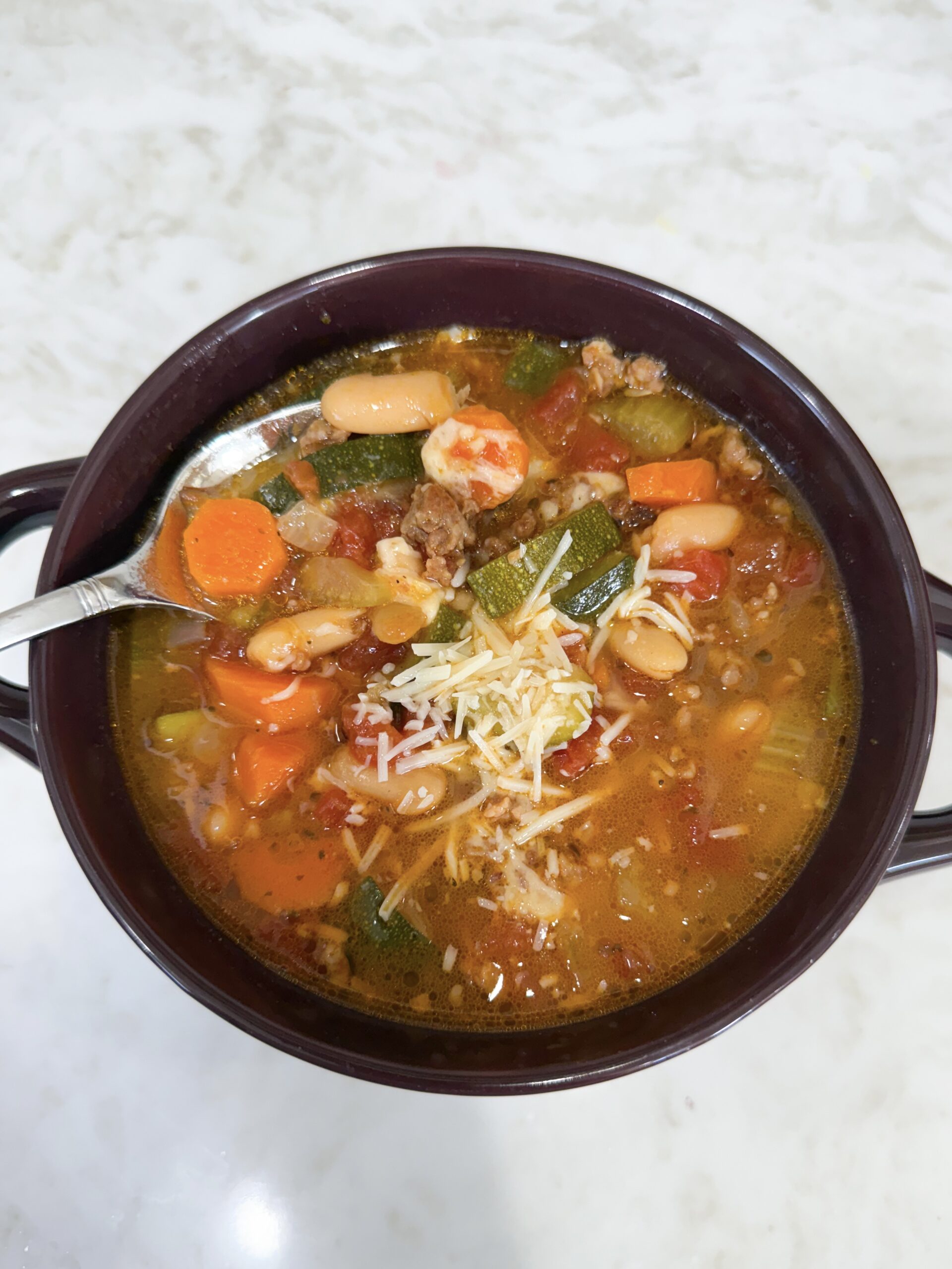 Bowl of Italian Vegetable and Sausage Soup with carrots, zucchini, beans, and sausage in a tomato broth