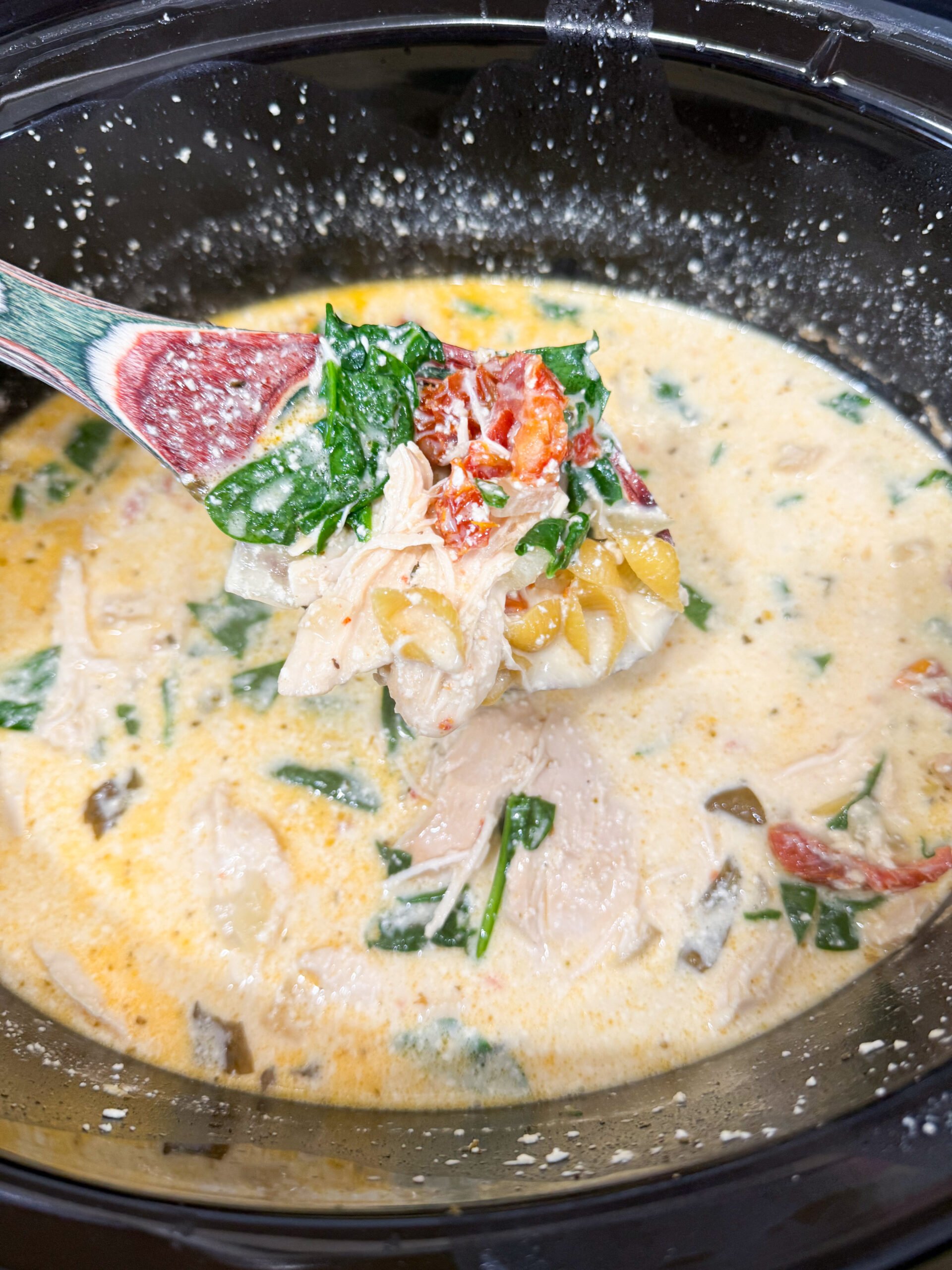 Pasta and spinach being stirred into soup