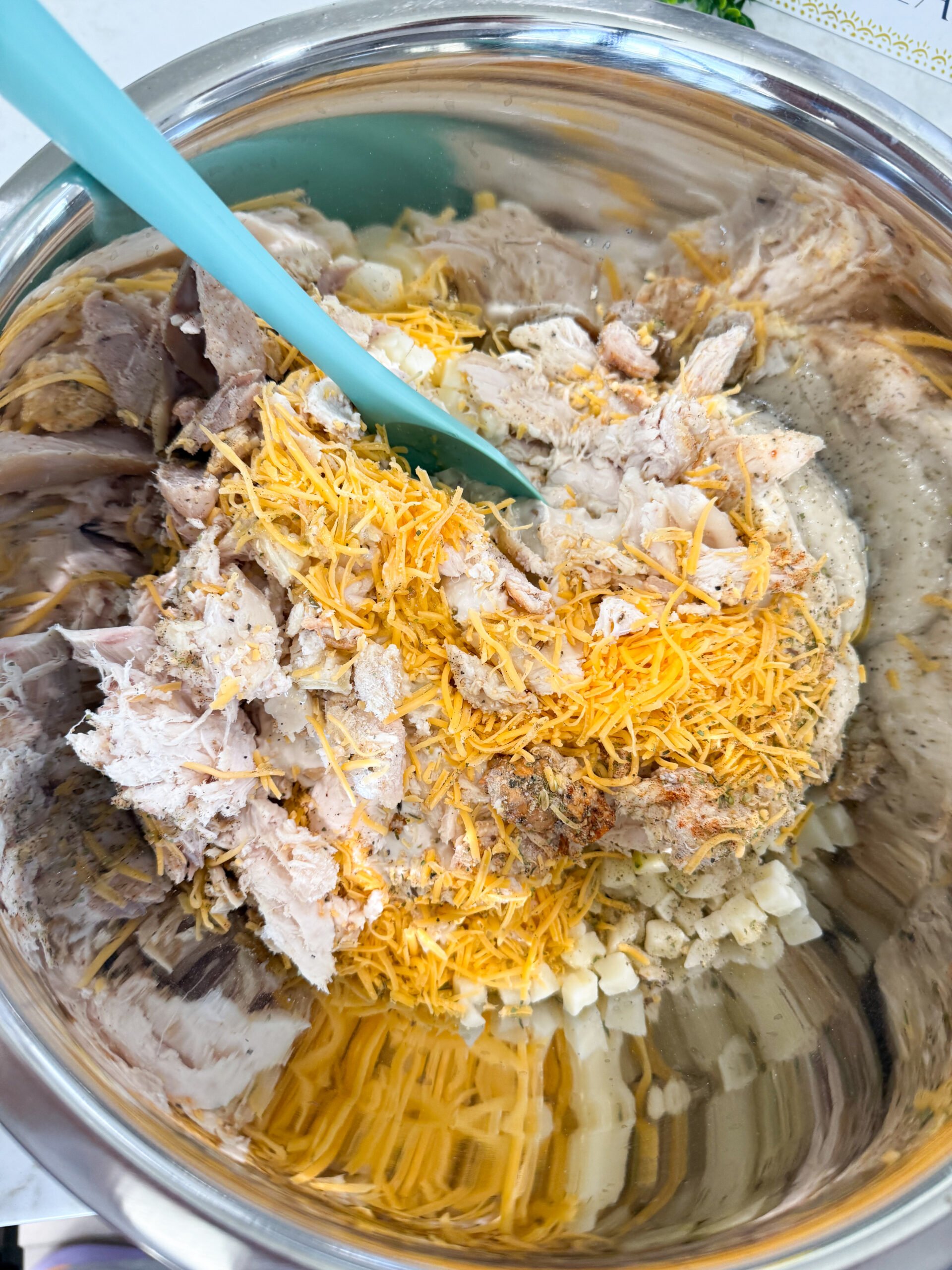 Shredded chicken, hash browns, soup, onion dip, cheese, and seasonings mixed together in a large bowl.