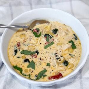 Bowl of creamy Slow Cooker Marry Me Chicken Soup with pasta, spinach, and sun-dried tomatoes