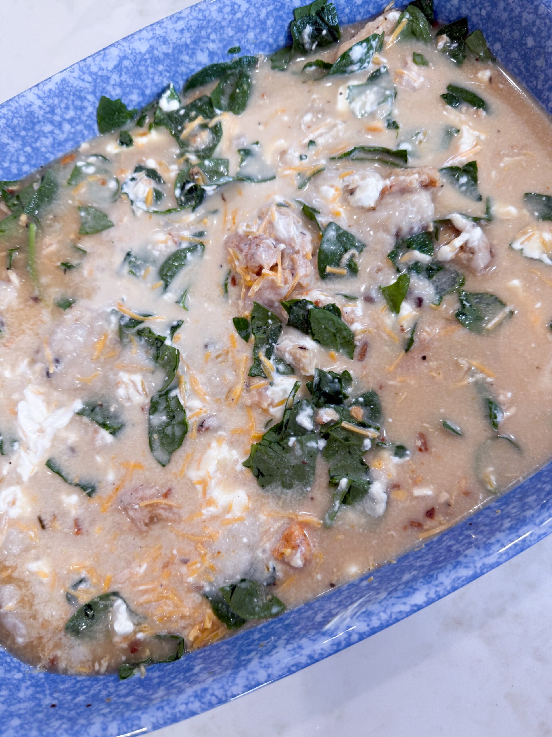 The creamy orzo and chicken mixture is spread into a casserole dish—Spinach Chicken Orzo Casserole is ready for the oven!