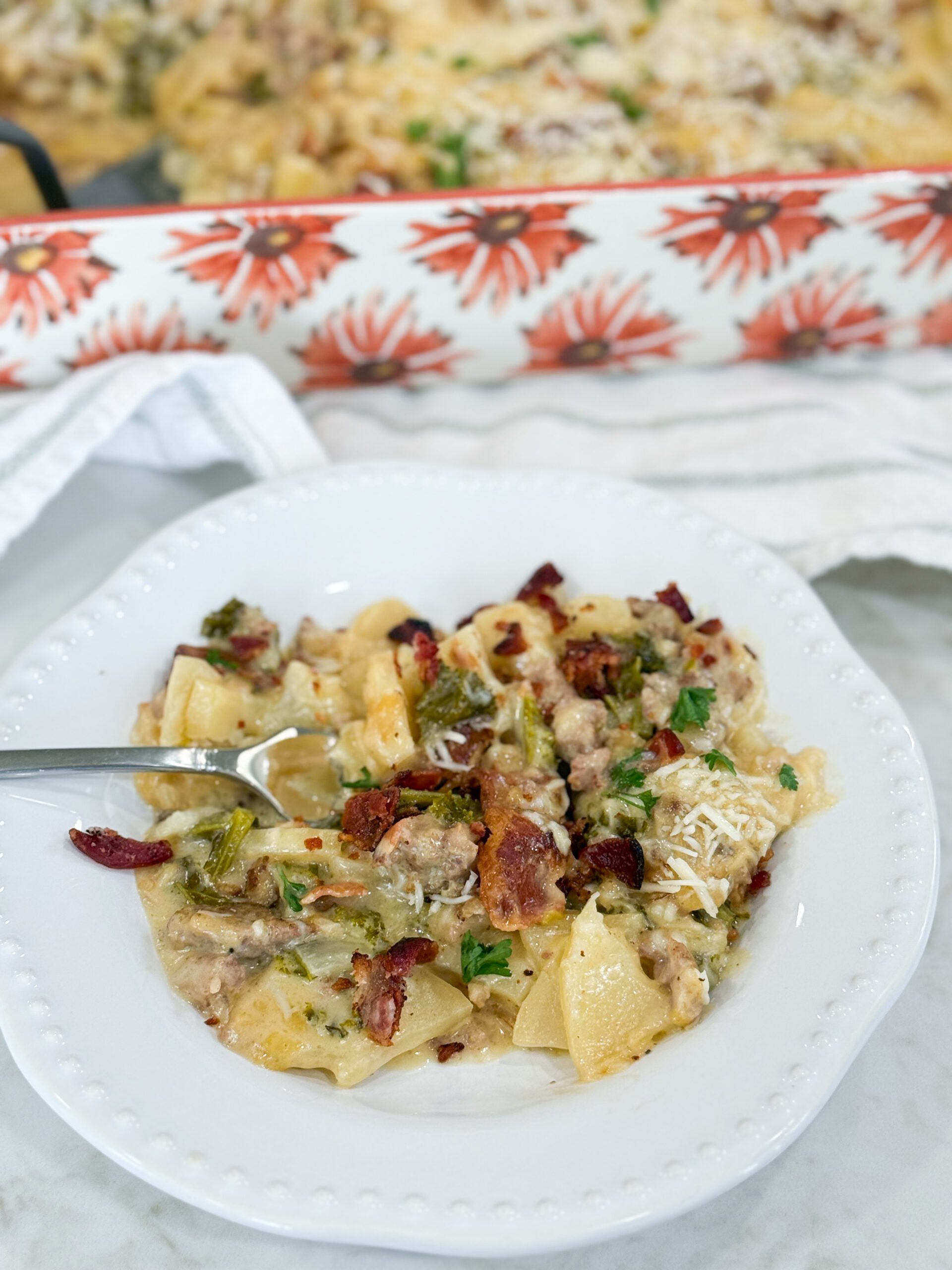 Serving of Zuppa Toscana Casserole plated with layers of potato, kale, sausage, bacon, and creamy sauce.
