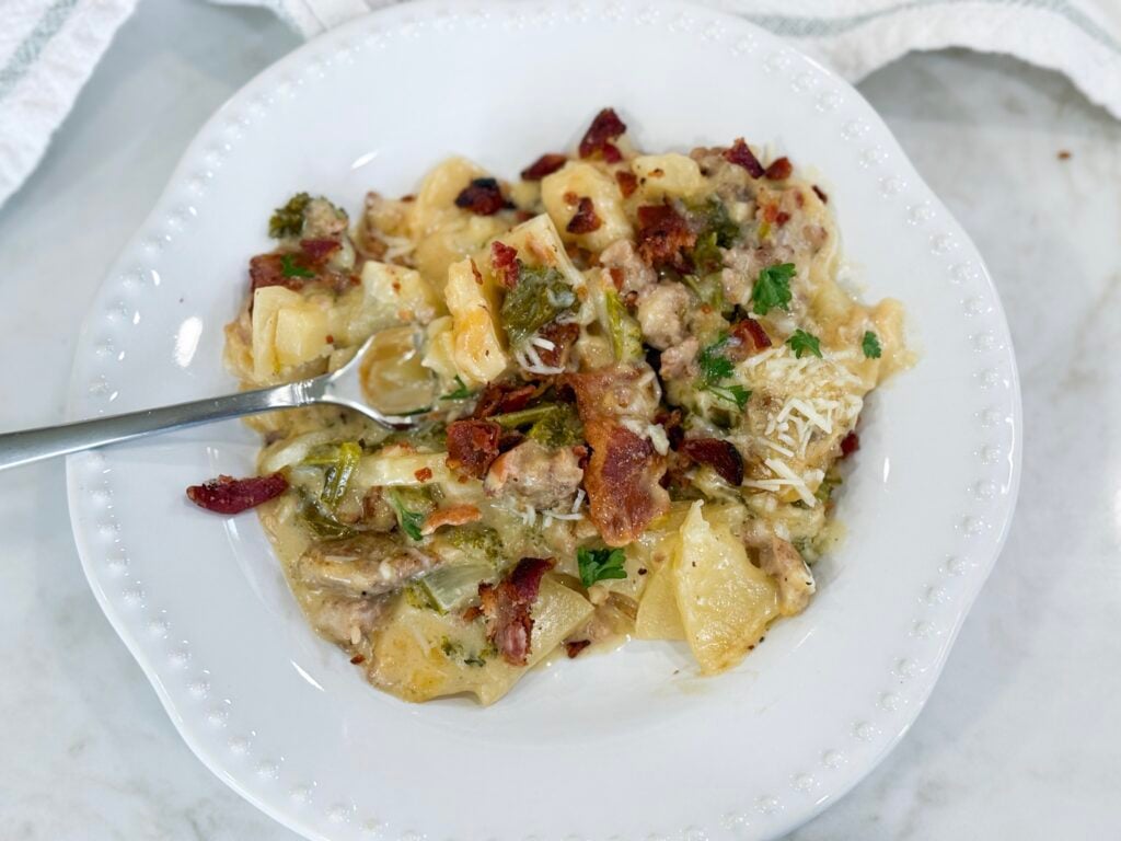 Serving of Zuppa Toscana Casserole plated with layers of potato, kale, sausage, bacon, and creamy sauce.