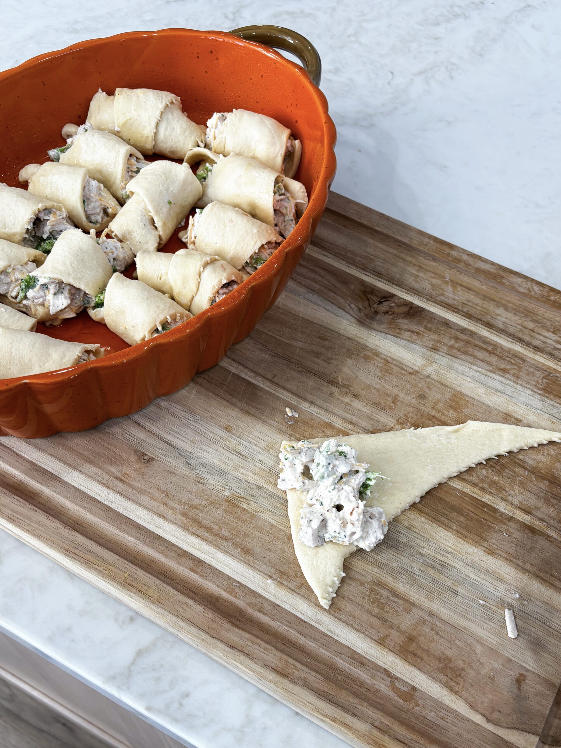 Rolling chicken mixture into crescent dough triangles
