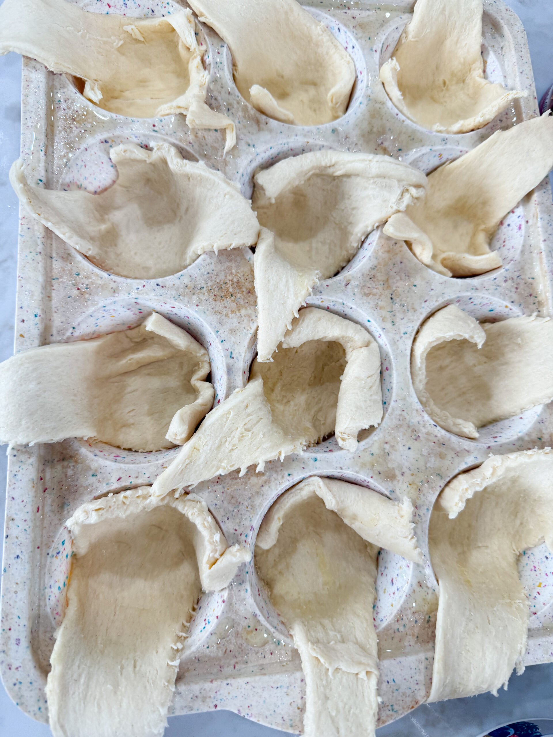 Pressing crescent dough into muffin tin