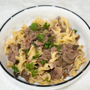 Slow cooker beef stroganoff served with noodles and parsley