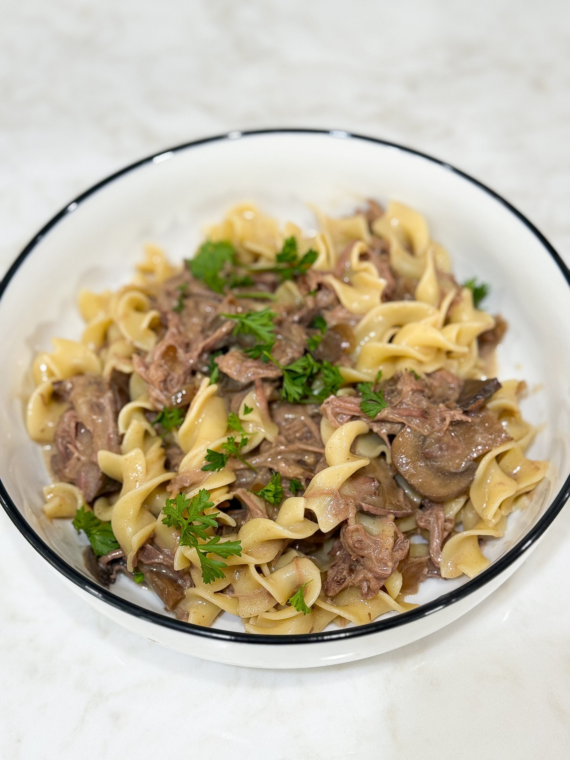 Slow cooker beef stroganoff served with noodles and parsley