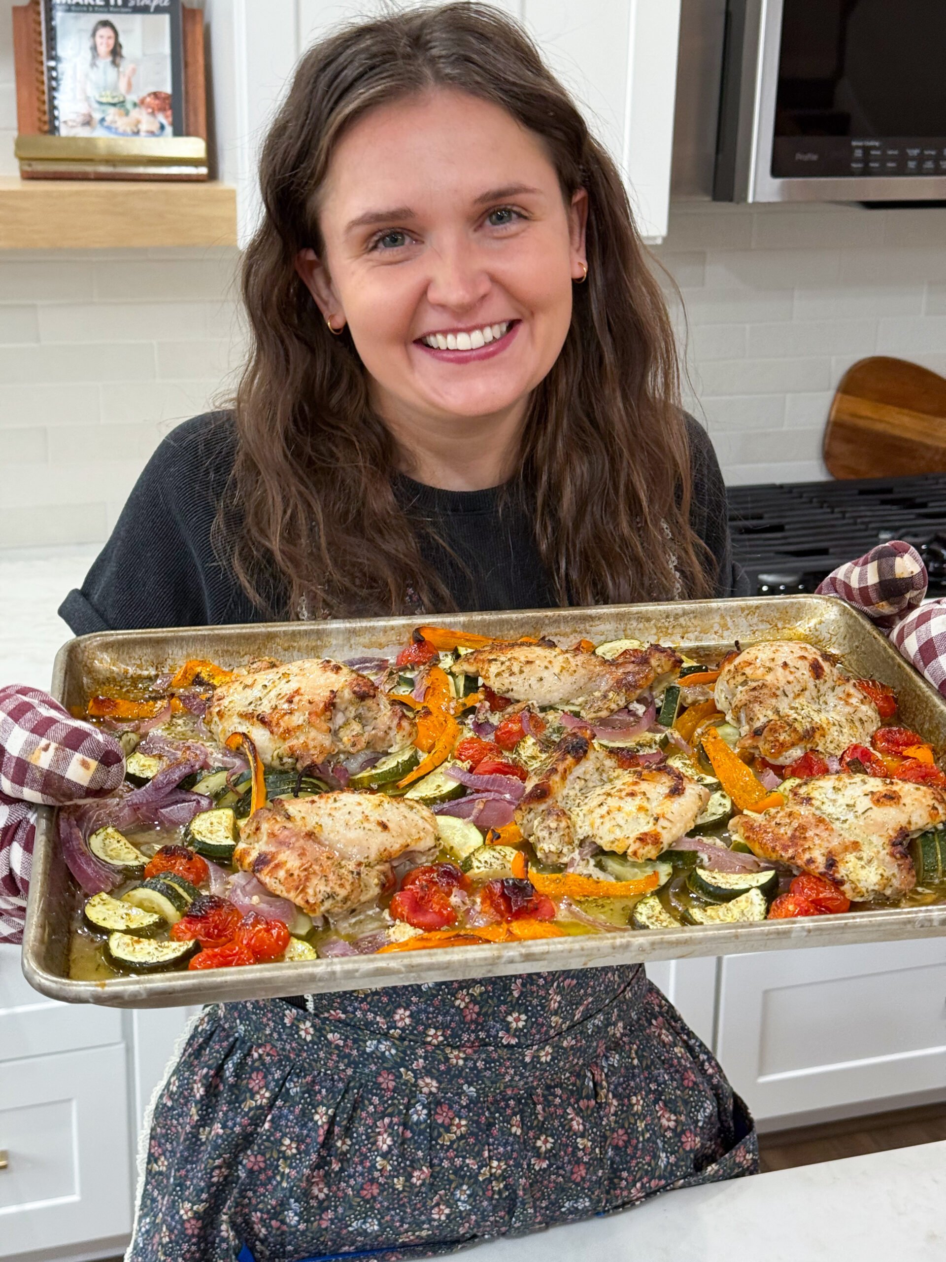 Julia holding finished sheet pan of greek chicken meal