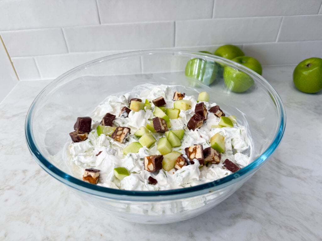 Snickers apple salad with chopped Granny Smith apples, candy pieces, and whipped topping