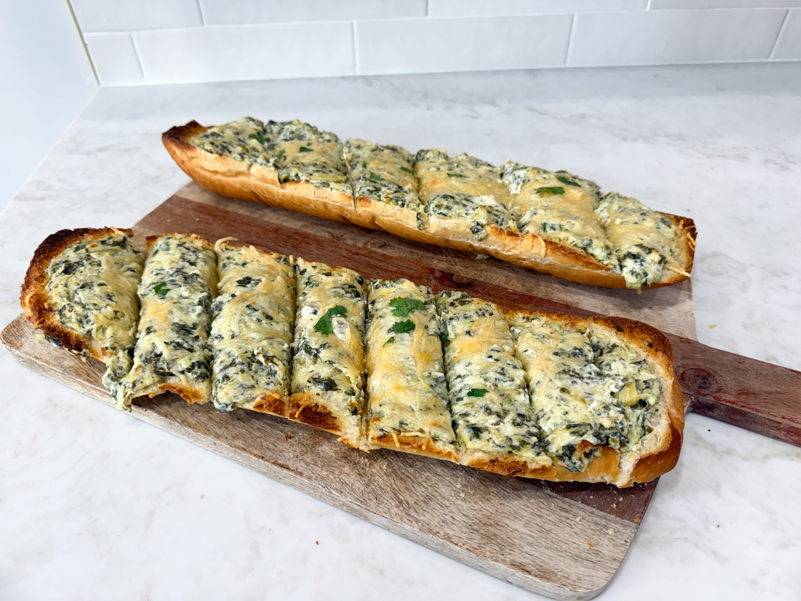 Spinach artichoke bread topped with melted Parmesan cheese